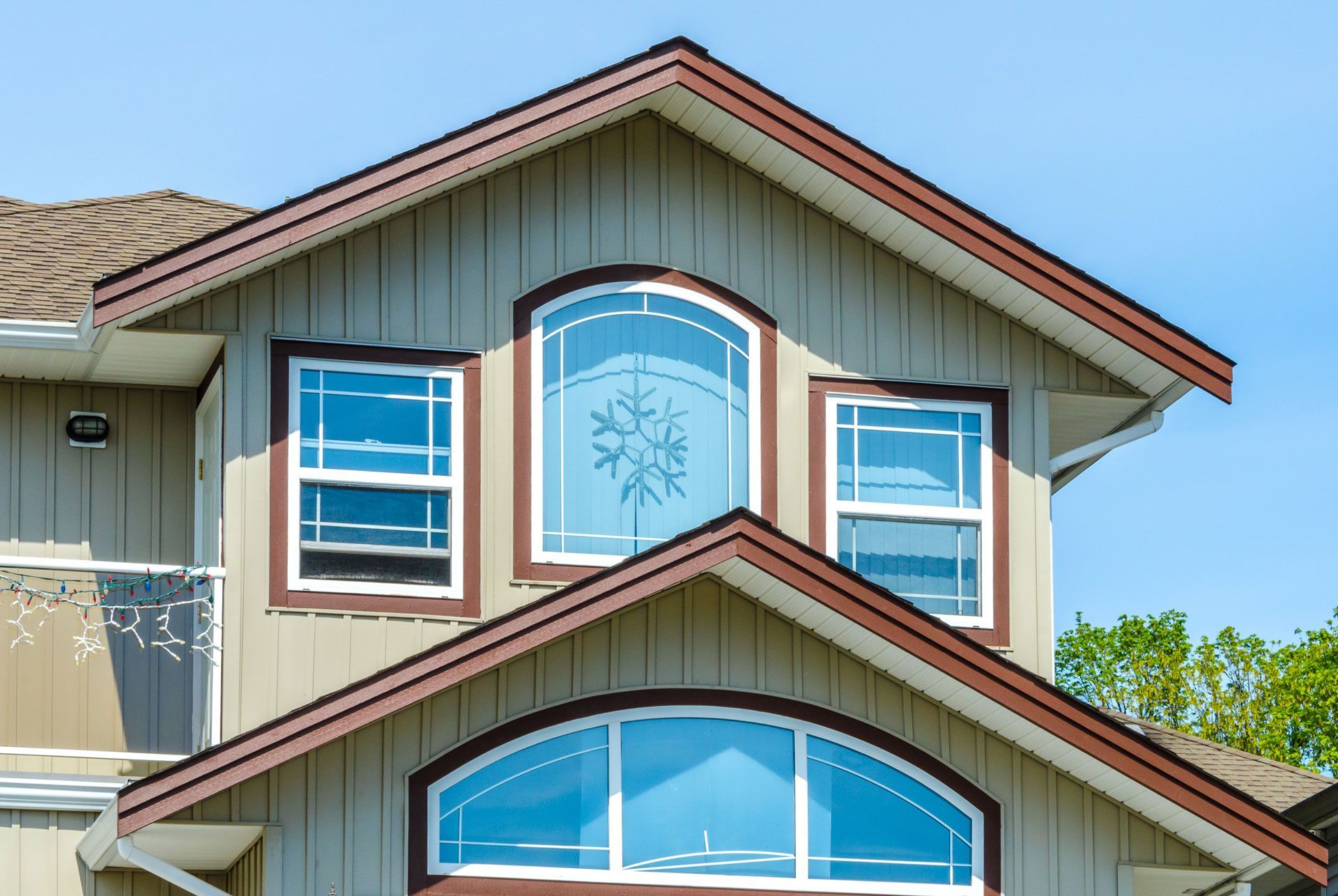 Tan house with brown trim and arched windows against a blue sky.