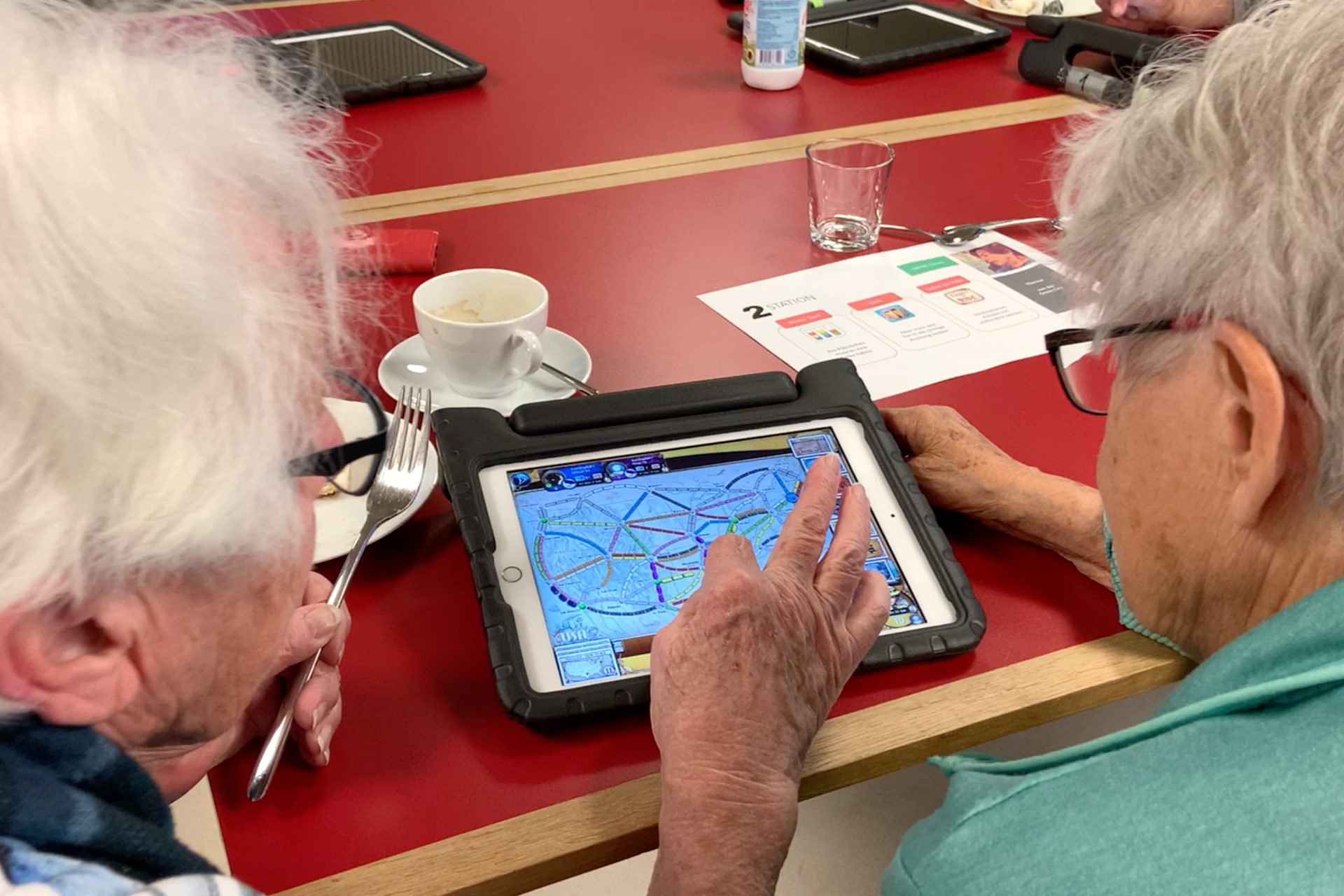 Zwei ältere Frauen gamen gemeinsam auf einem iPad.