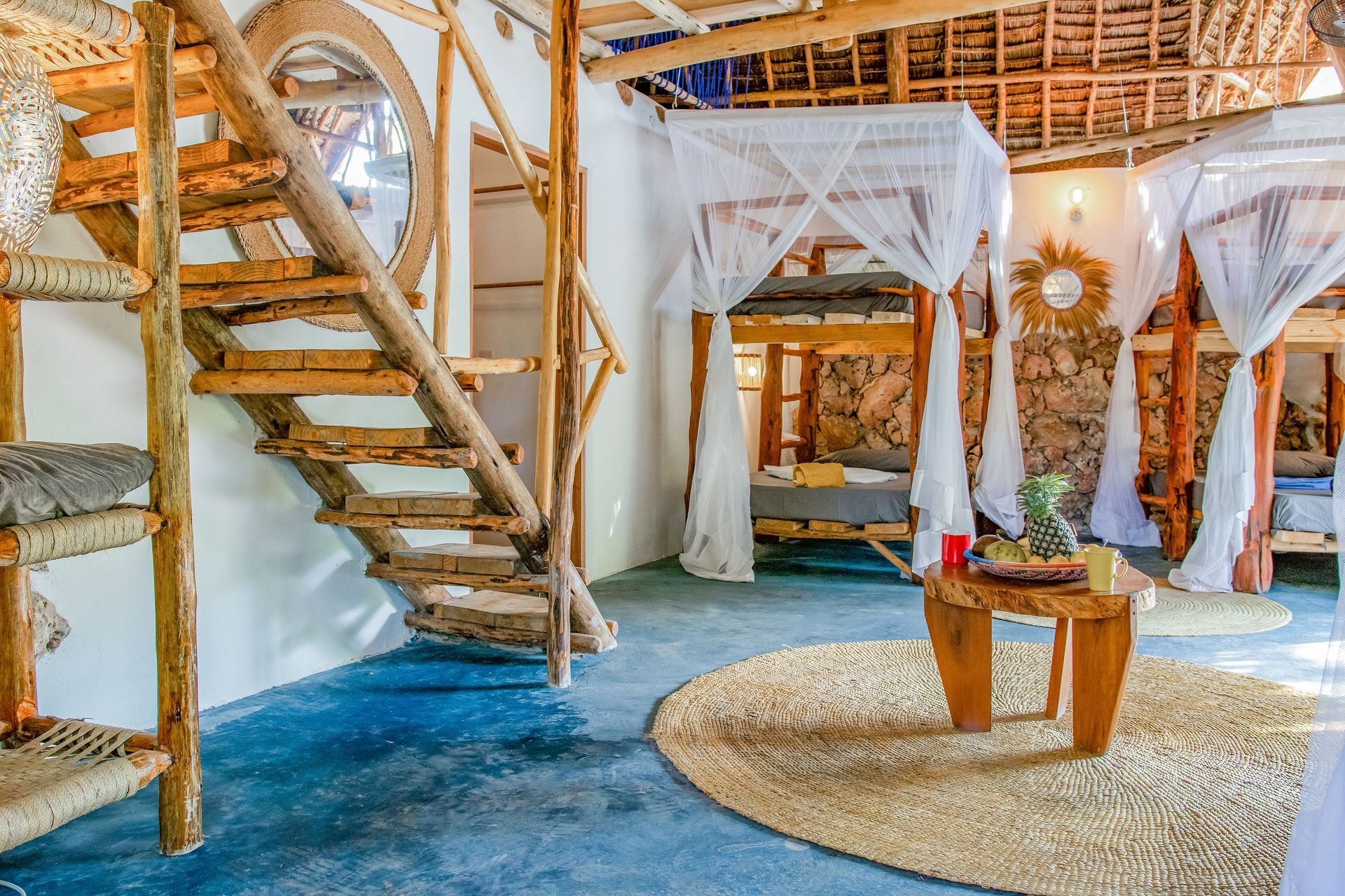 Rustic interior with bunk beds, wooden staircase, and table with fruit.