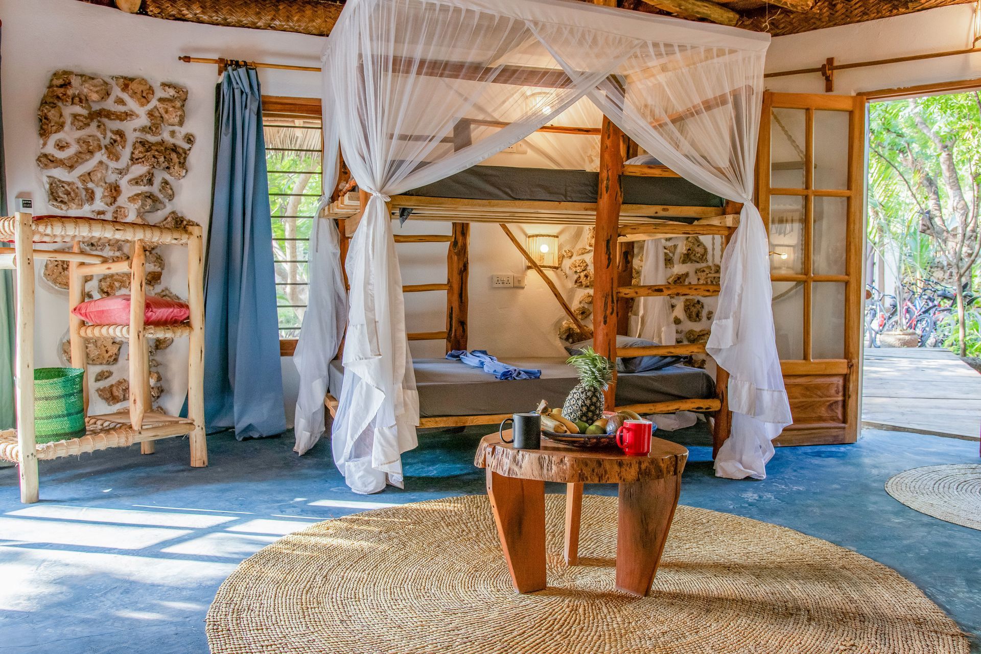 Bedroom with bunk beds, stone wall, wood furniture, and a mosquito net.