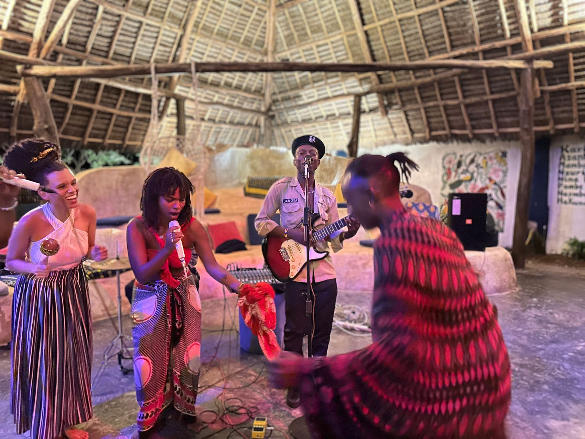 A group of people are standing around a man playing a guitar.