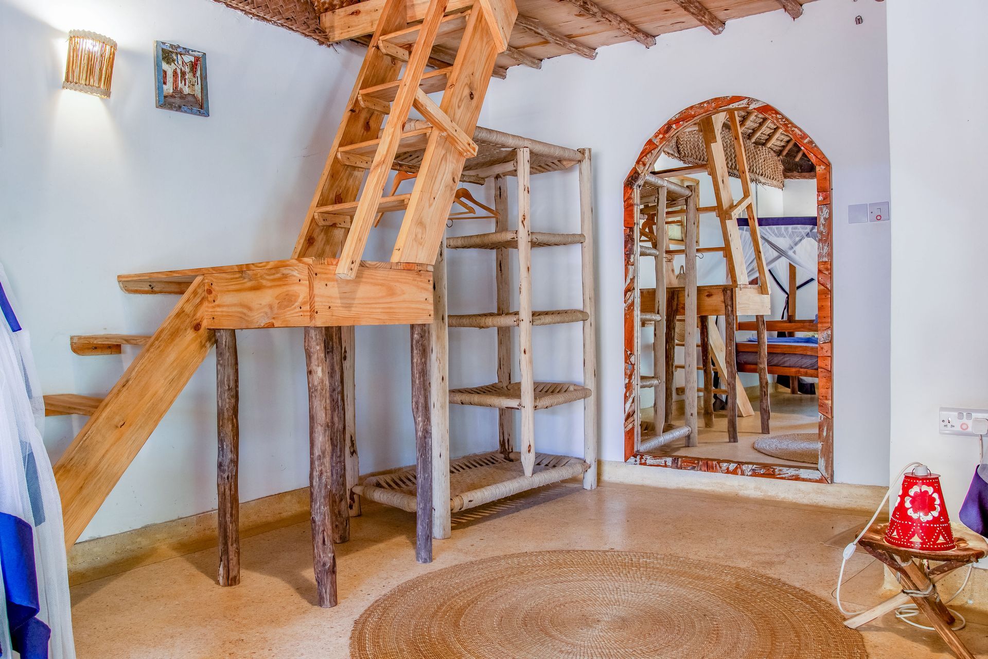 Wooden stairs and shelving in a rustic white-walled room with a circular rug.