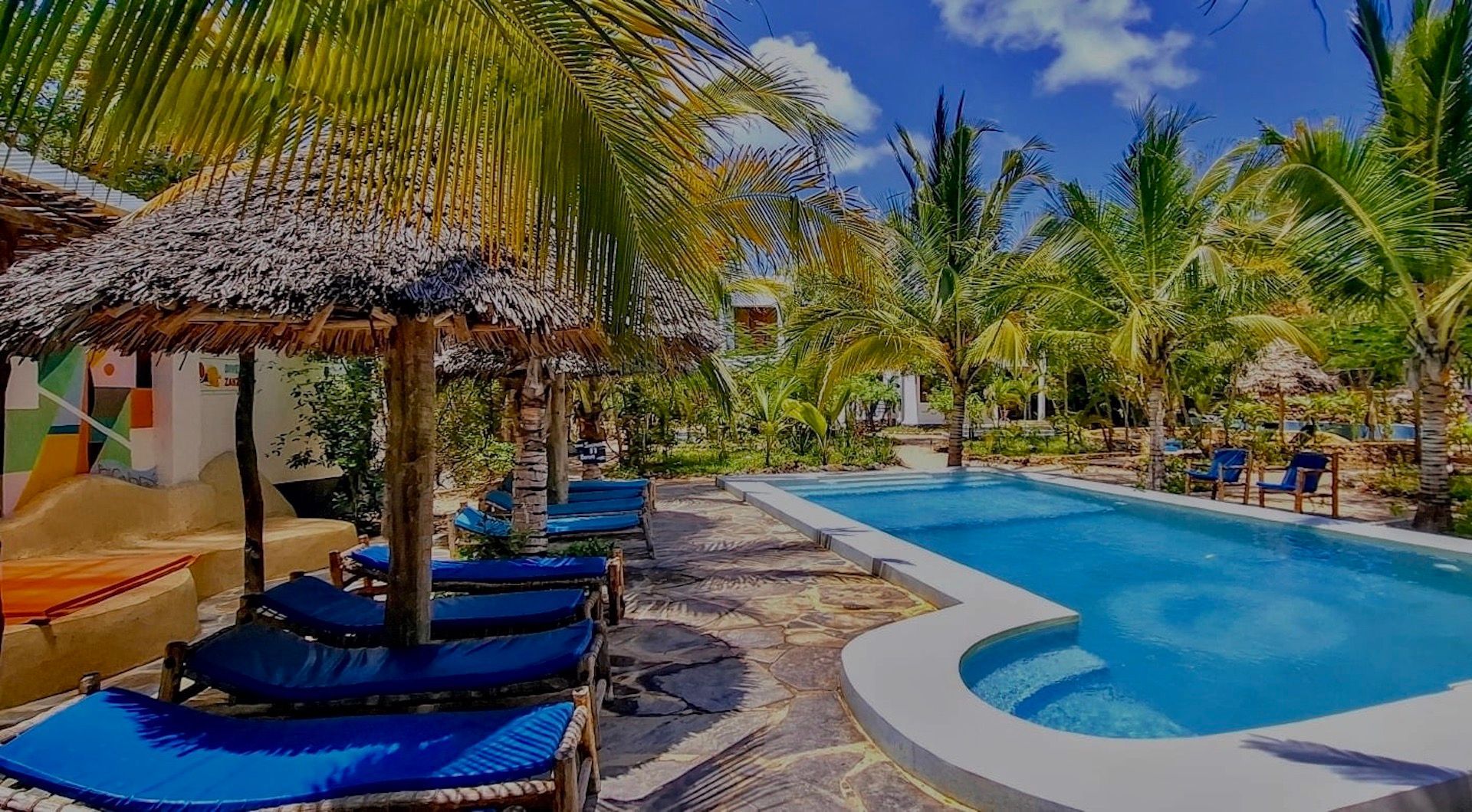 A large swimming pool surrounded by palm trees and chairs.