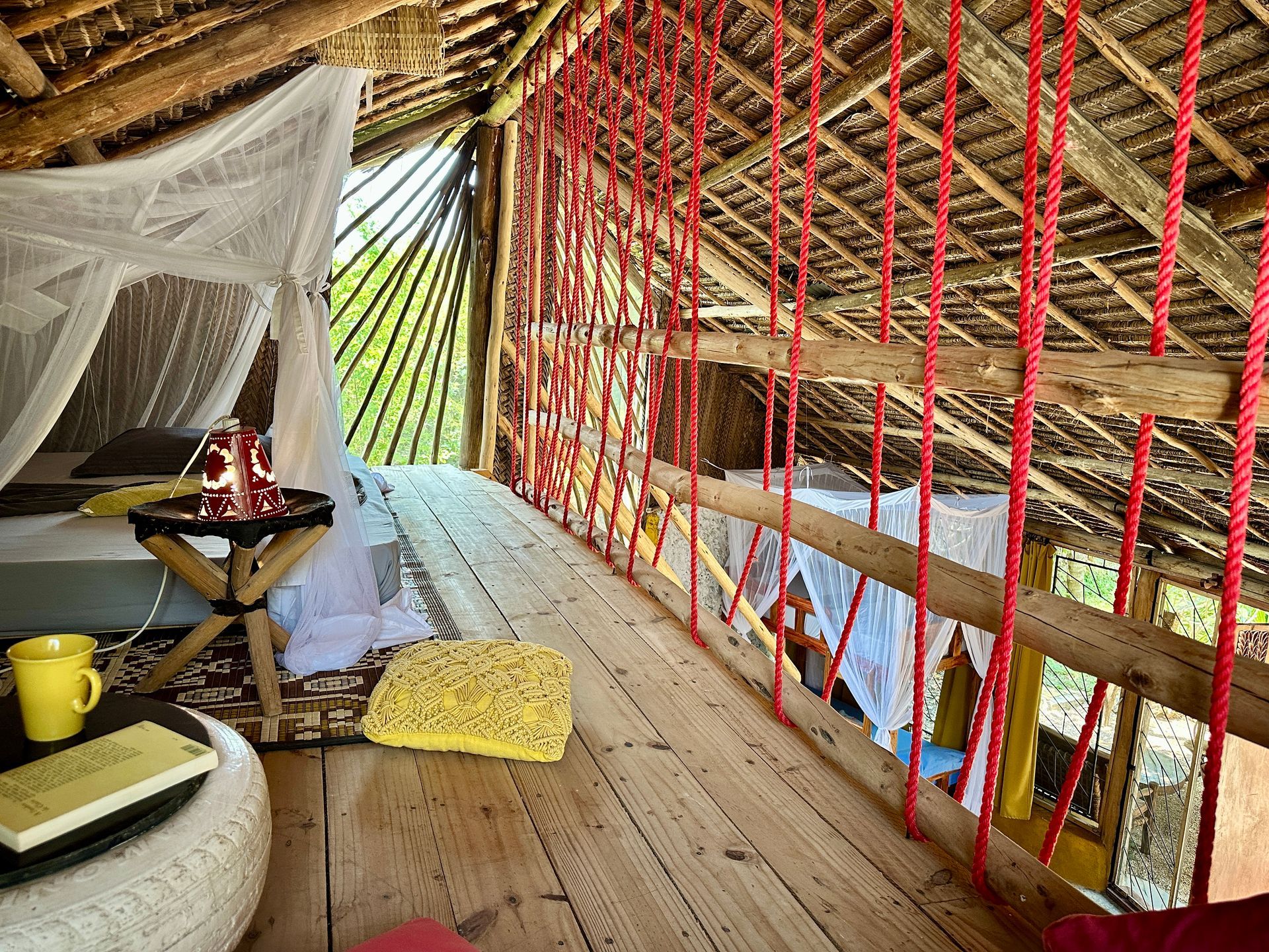 Wooden loft bedroom with canopy bed, red rope netting, yellow accents.