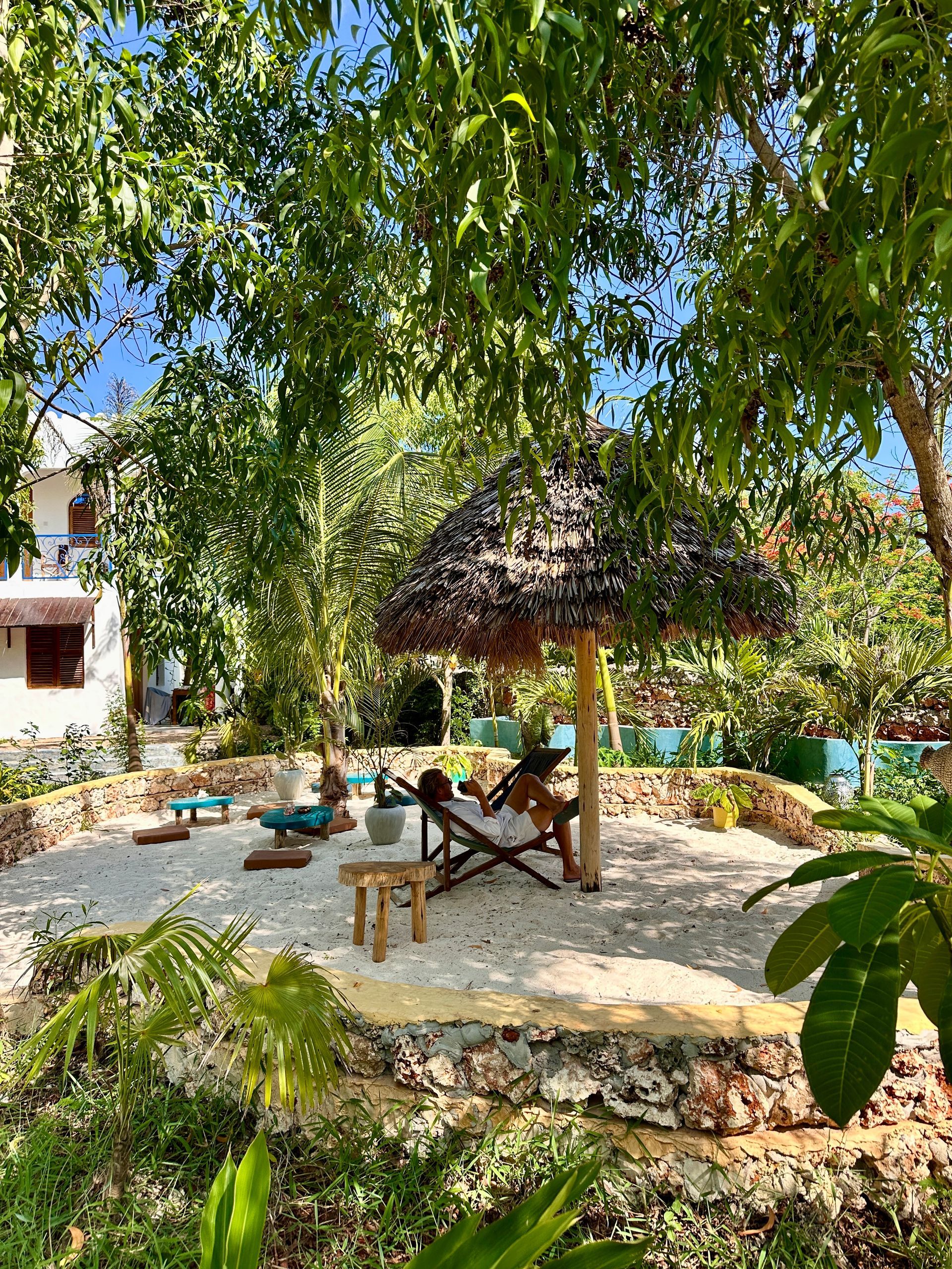 A thatched umbrella is sitting on top of a sandy area surrounded by trees.