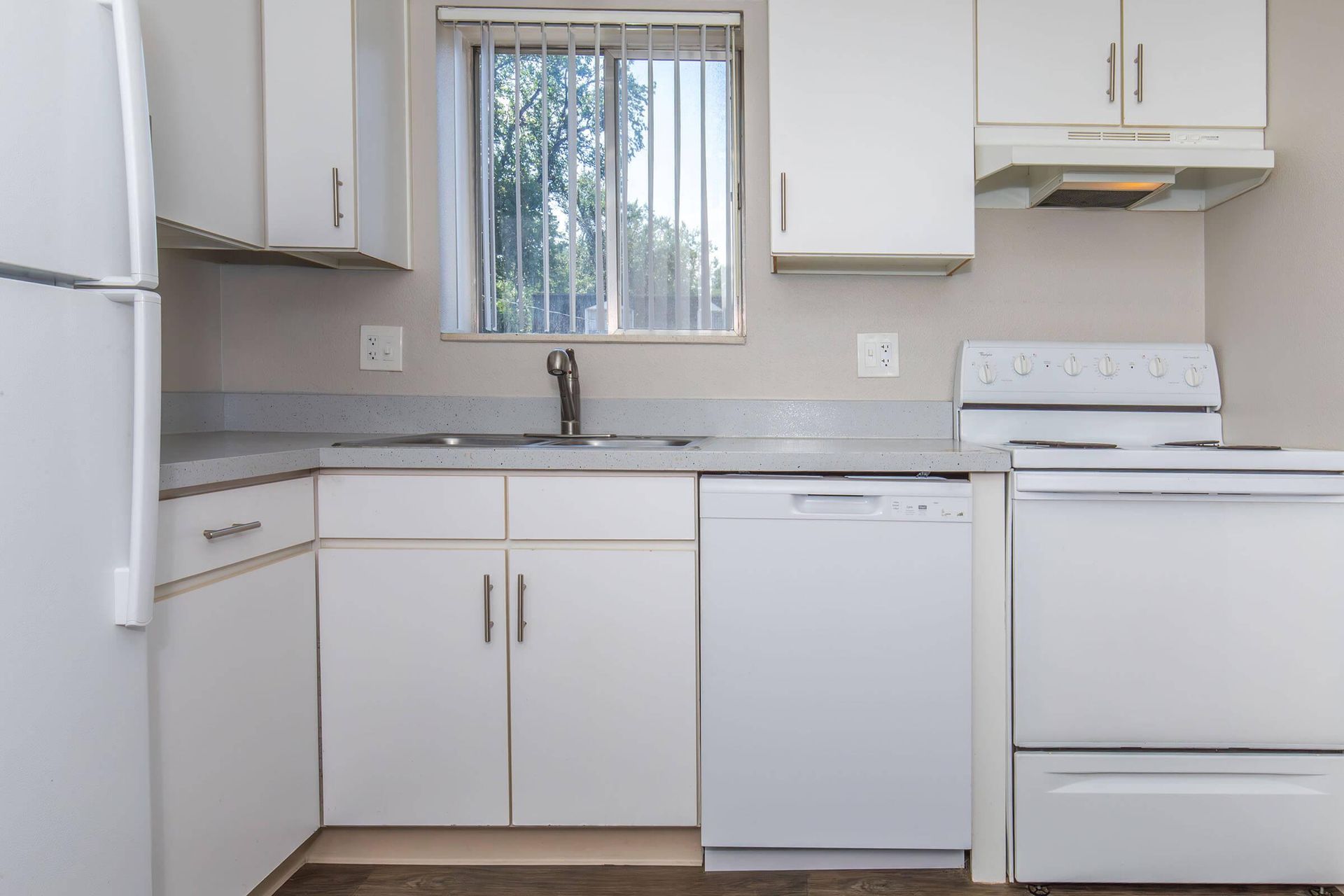 White kitchen with cabinets, appliances, and a window.
