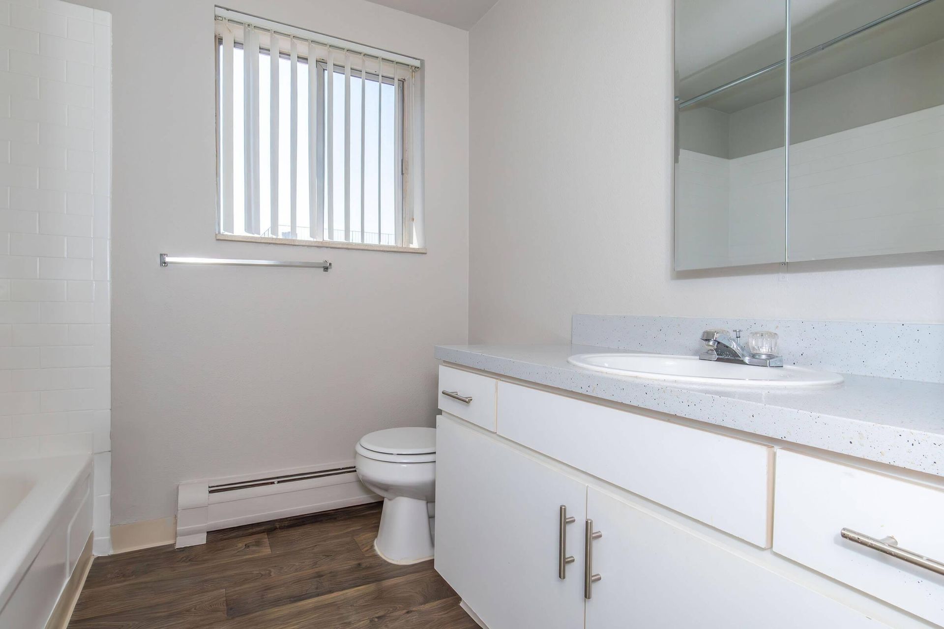 White bathroom with a window, vanity, toilet, and bathtub.