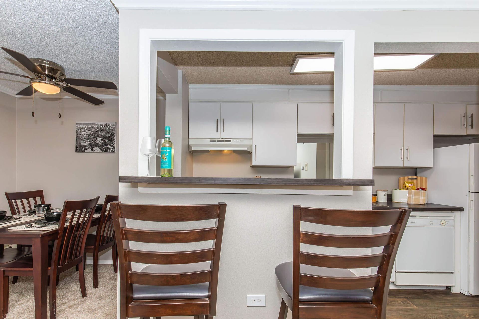 Interior view of a dining area with a kitchen pass-through and bar stools.