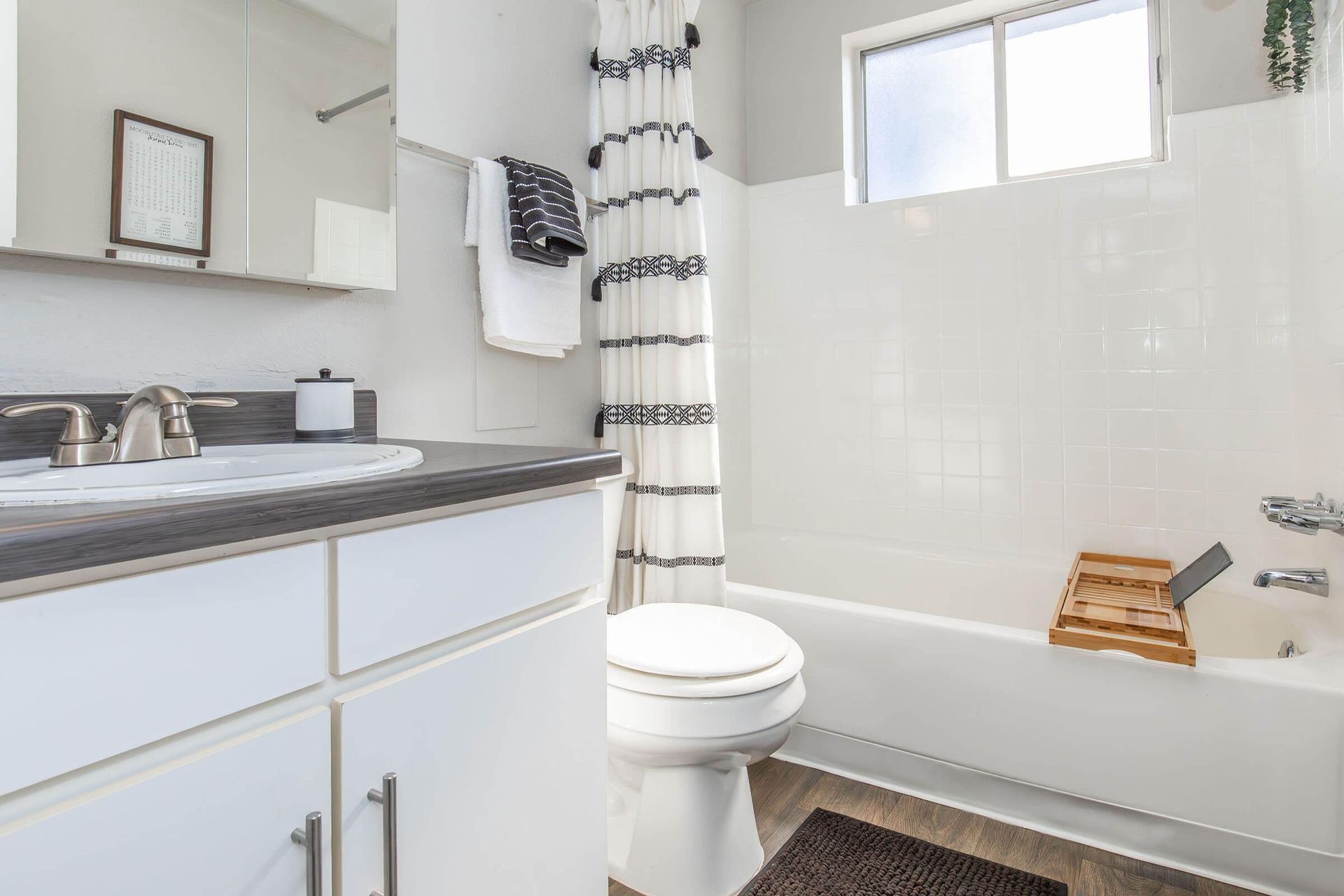 Bathroom with white tile, a bathtub, a toilet, a sink, and a shower curtain.