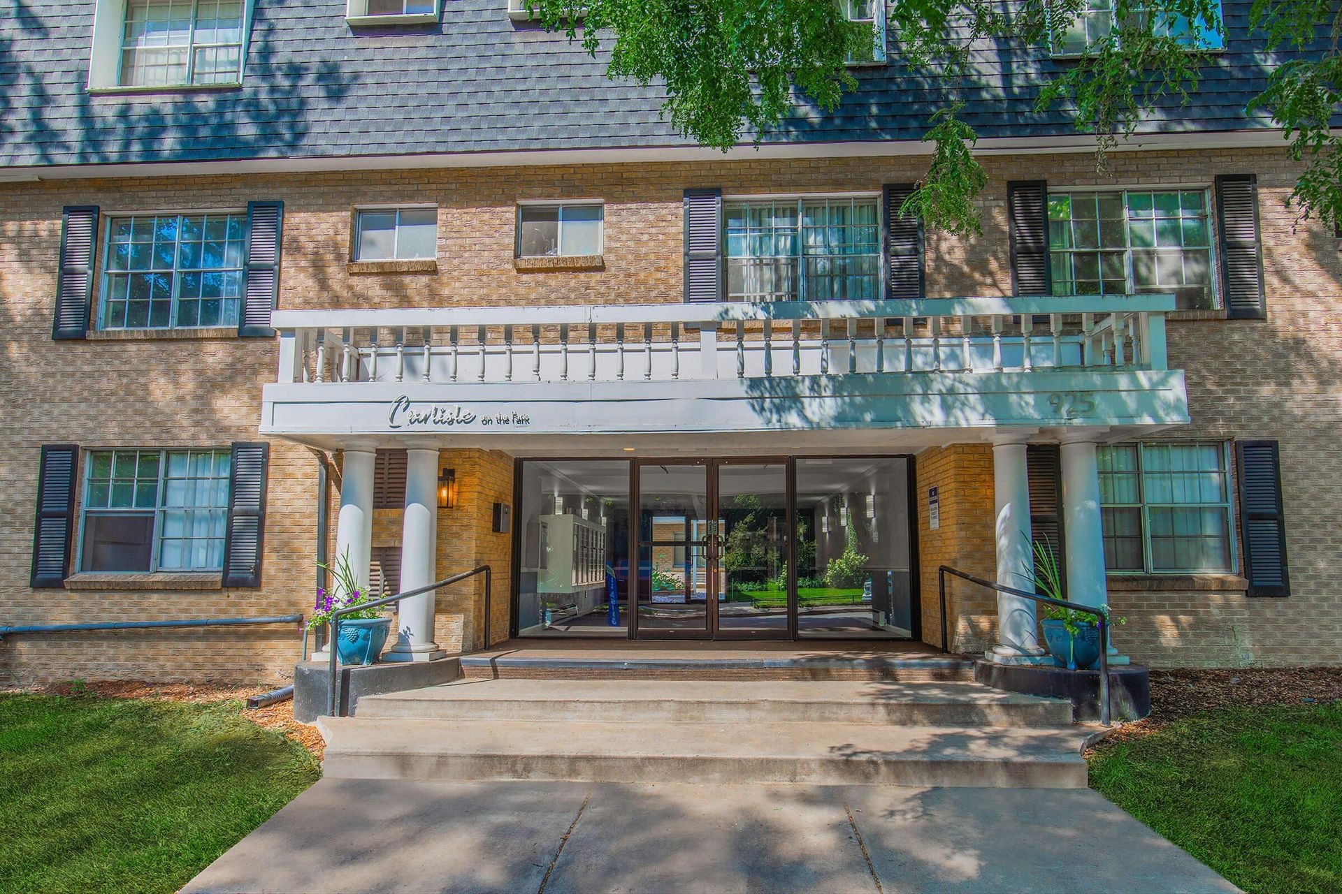 Apartment building with brick facade, glass entry doors, and a small balcony.