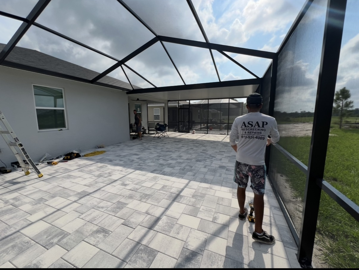 Person using a roller tool to install screen mesh into a window frame.