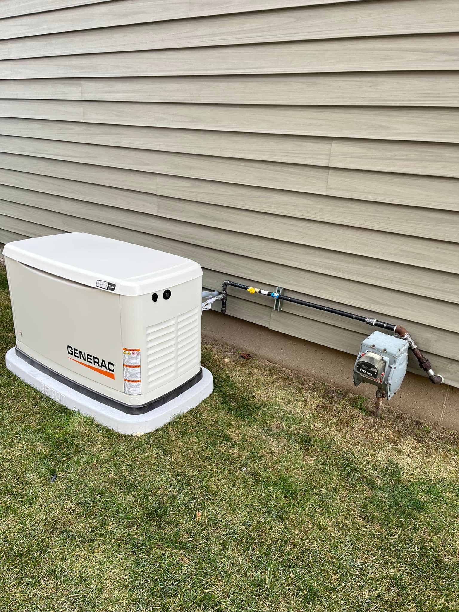 A generator is attached to the side of a house.