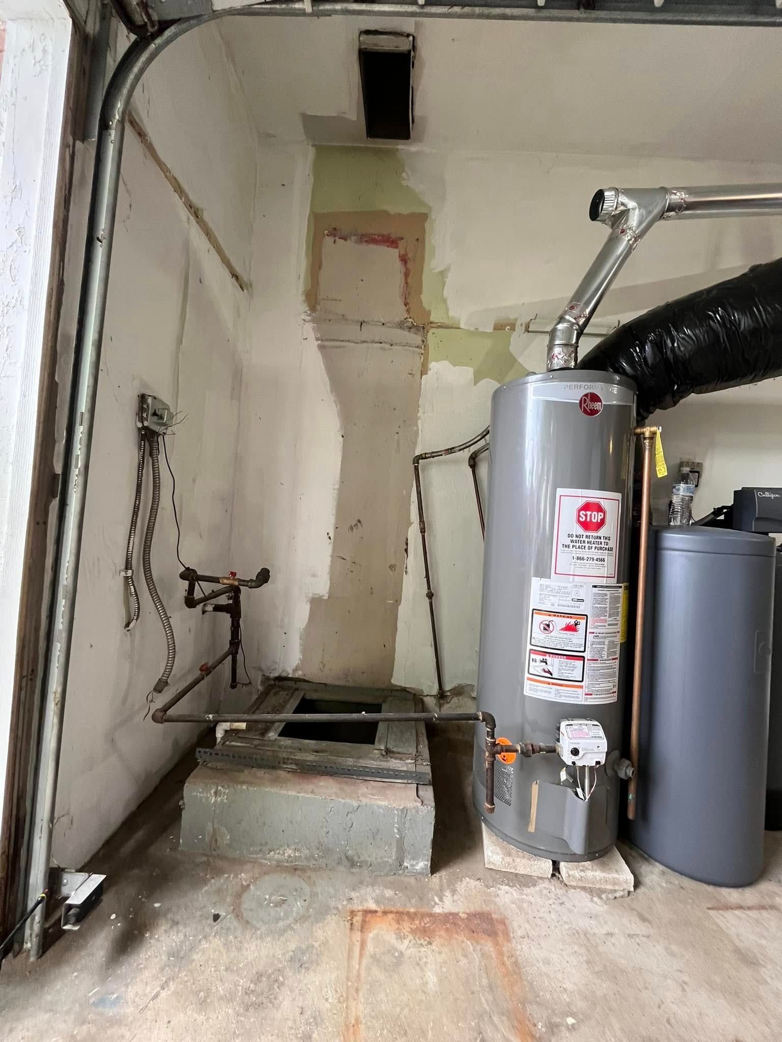 A water heater is sitting in a garage next to a door.