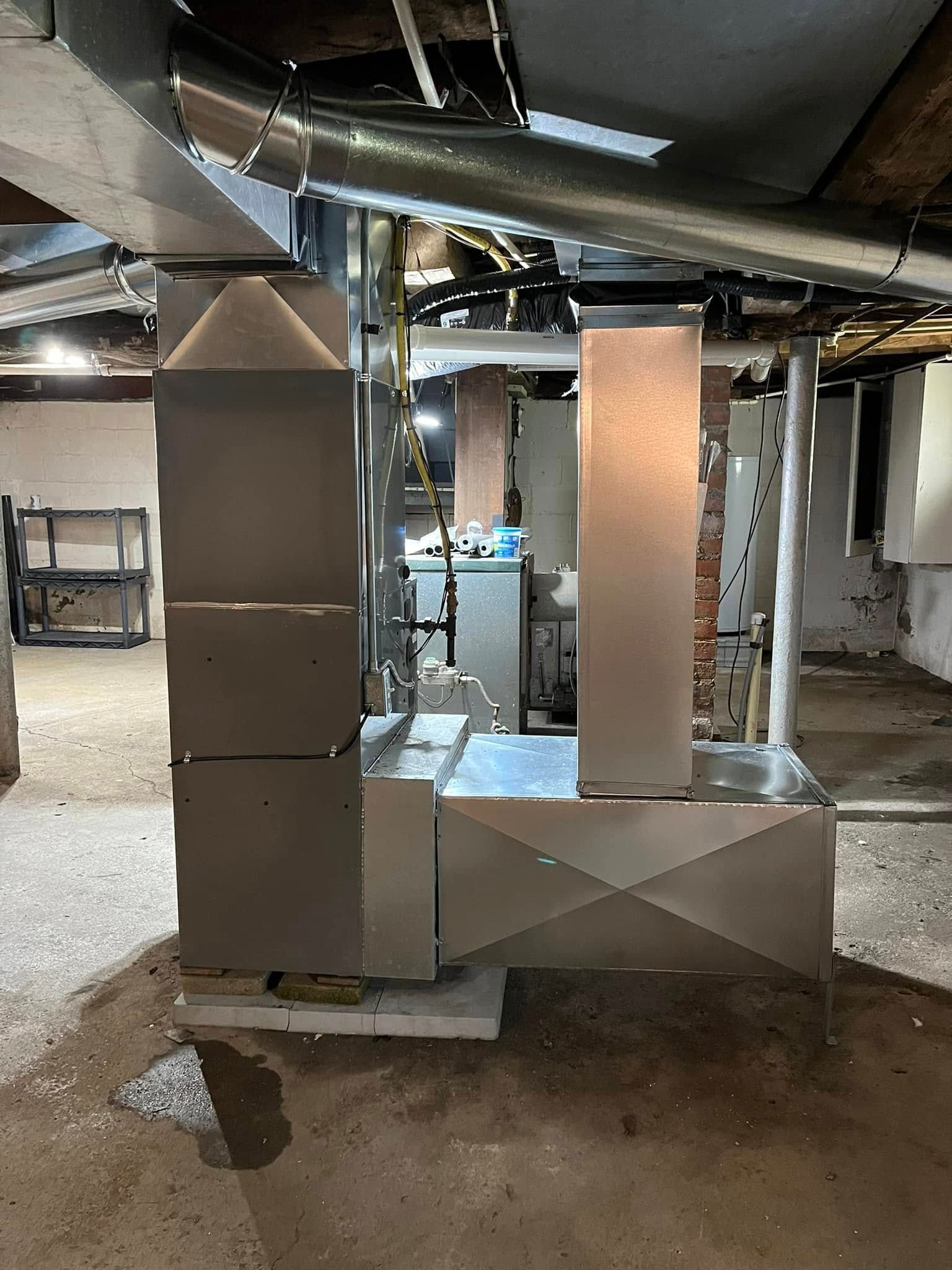 A stainless steel ducting system is being installed in a basement.