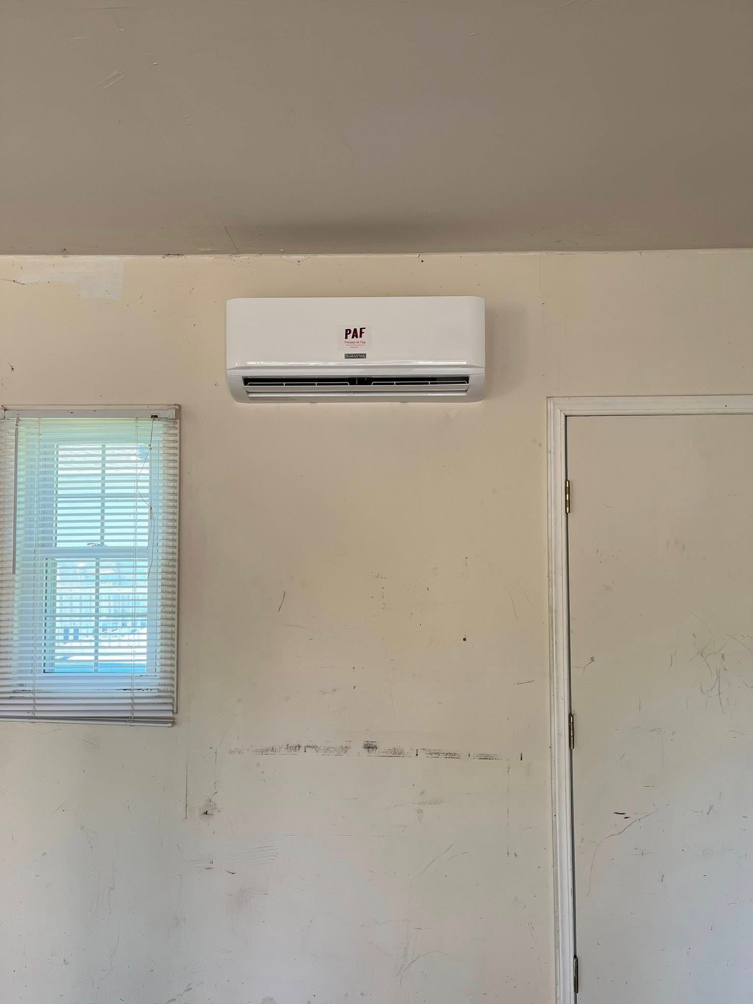 A room with a window and a wall mounted air conditioner.