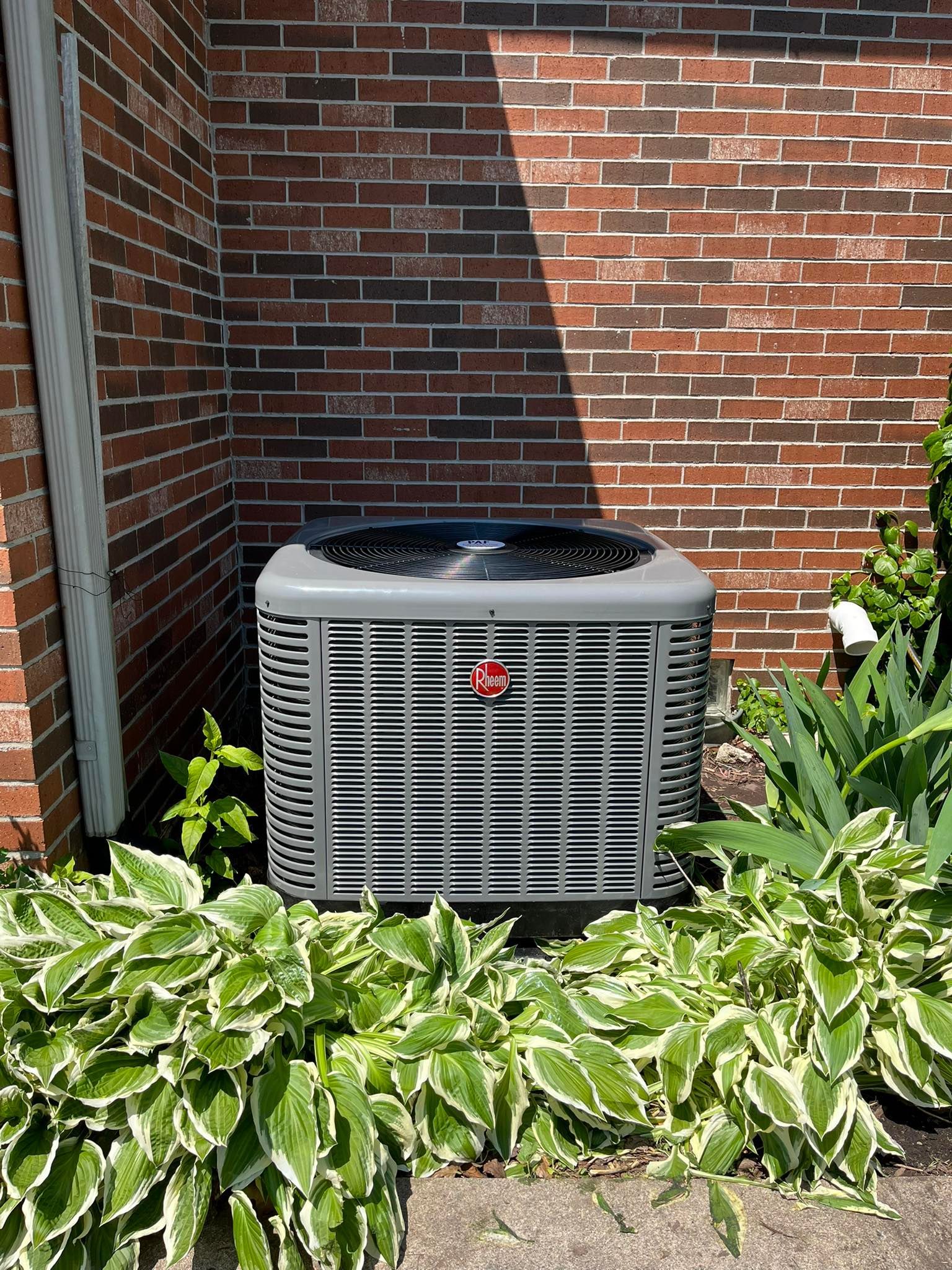 An air conditioner is sitting on the side of a brick building.