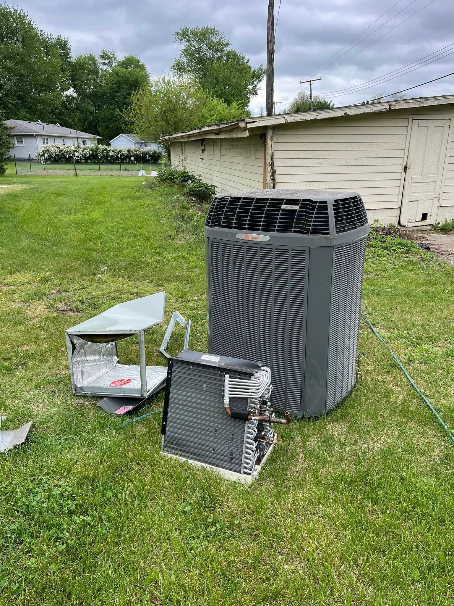 A broken air conditioner is sitting on top of a lush green field.