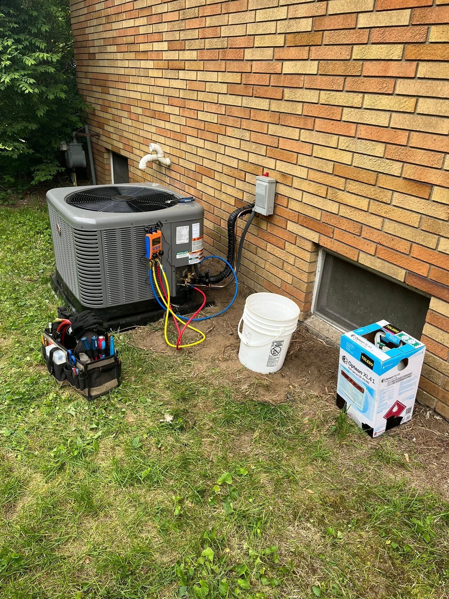 An air conditioner is being installed on the side of a brick building.