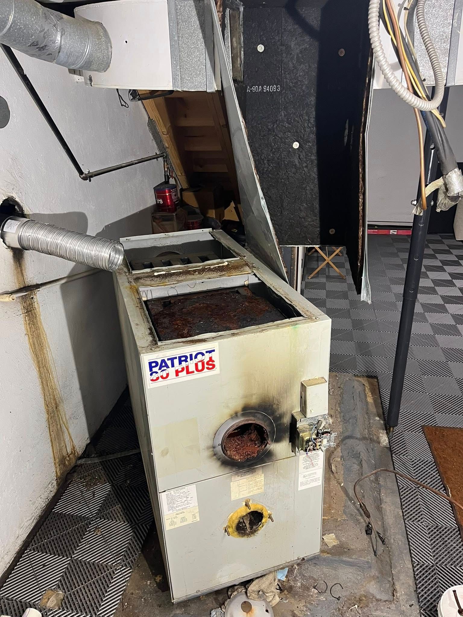 An old heater is sitting on the floor in a basement.