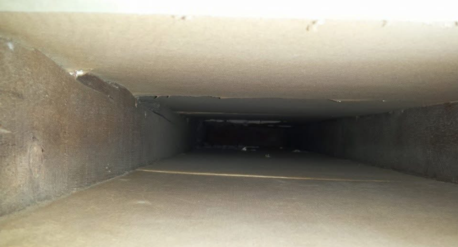 Looking down a dirty air vent in a building.