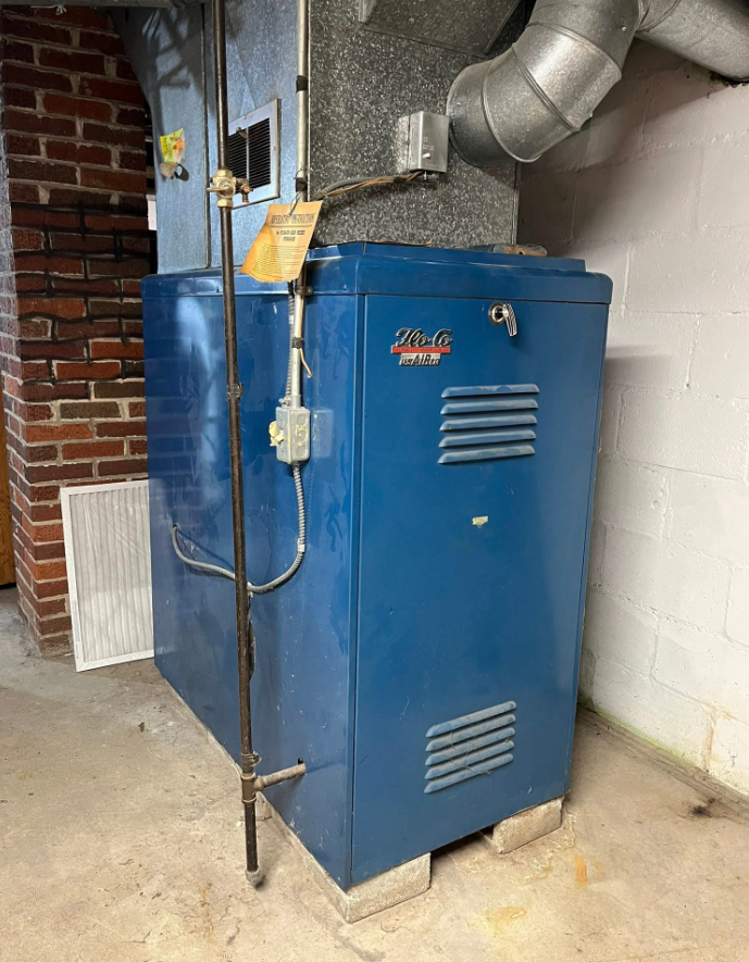 A broken air conditioner is sitting on top of a lush green field.