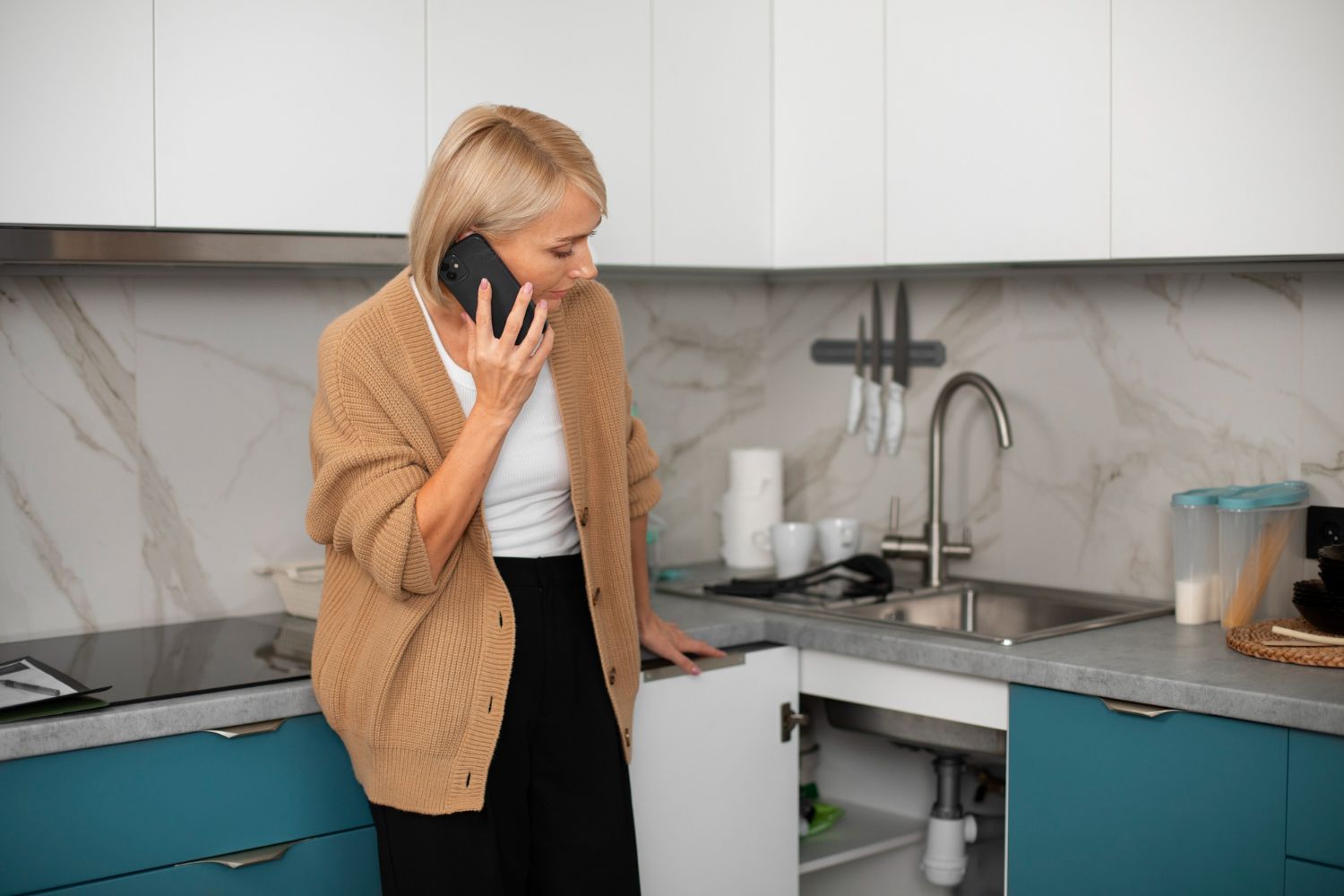 Woman on phone in a modern kitchen near the sink and stove
