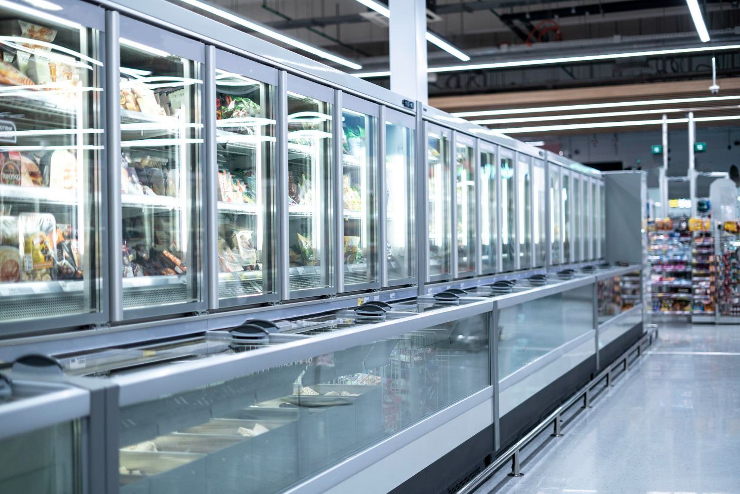 Empty refrigerated grocery aisle with glass-door freezers and polished floor