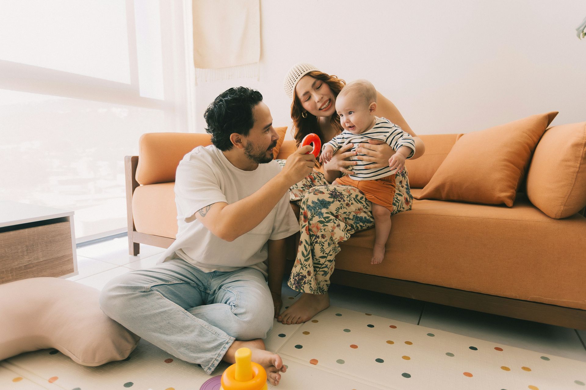 Family on a couch playing with a baby in a bright living room