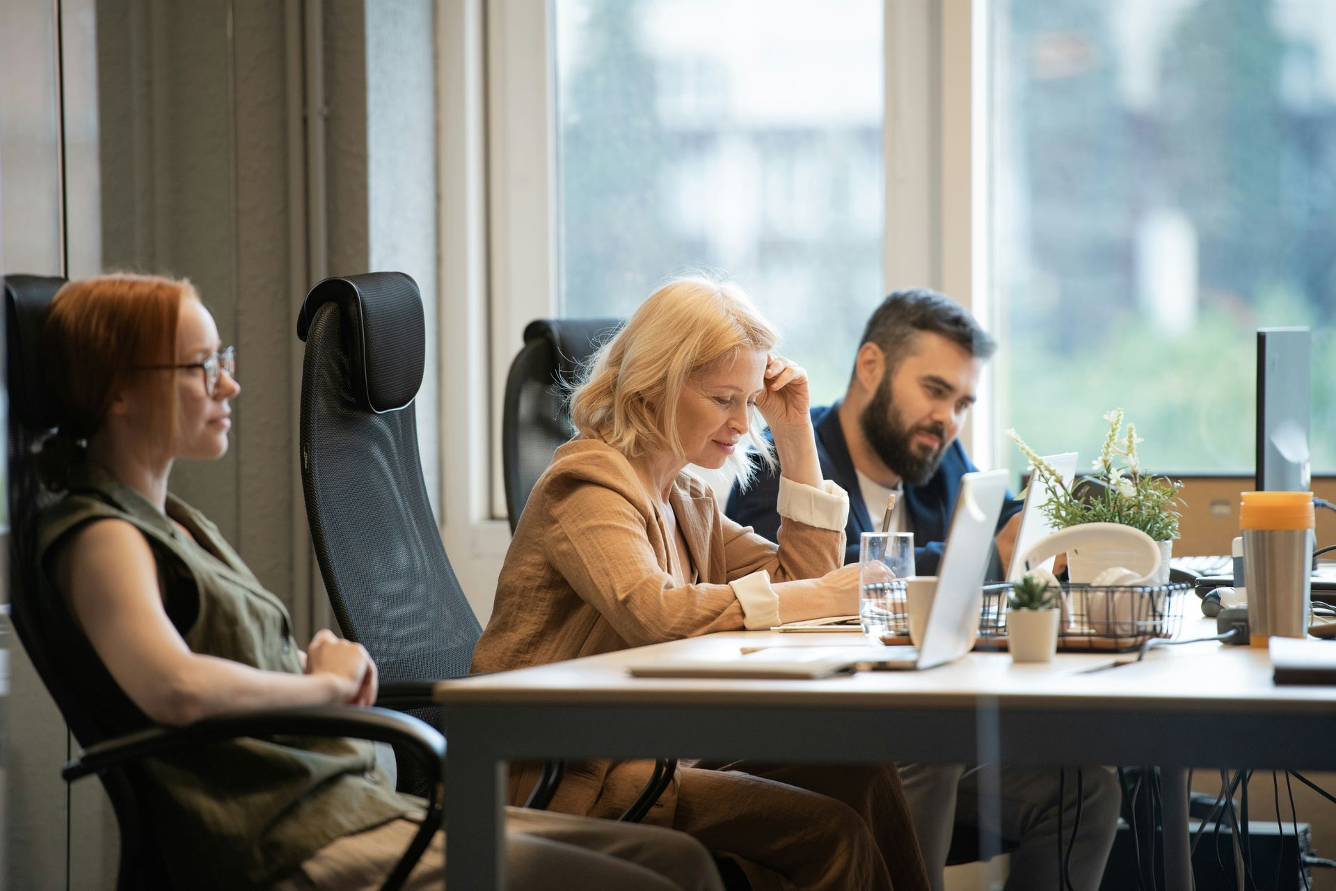 People working at a laptop in a bright office conference room