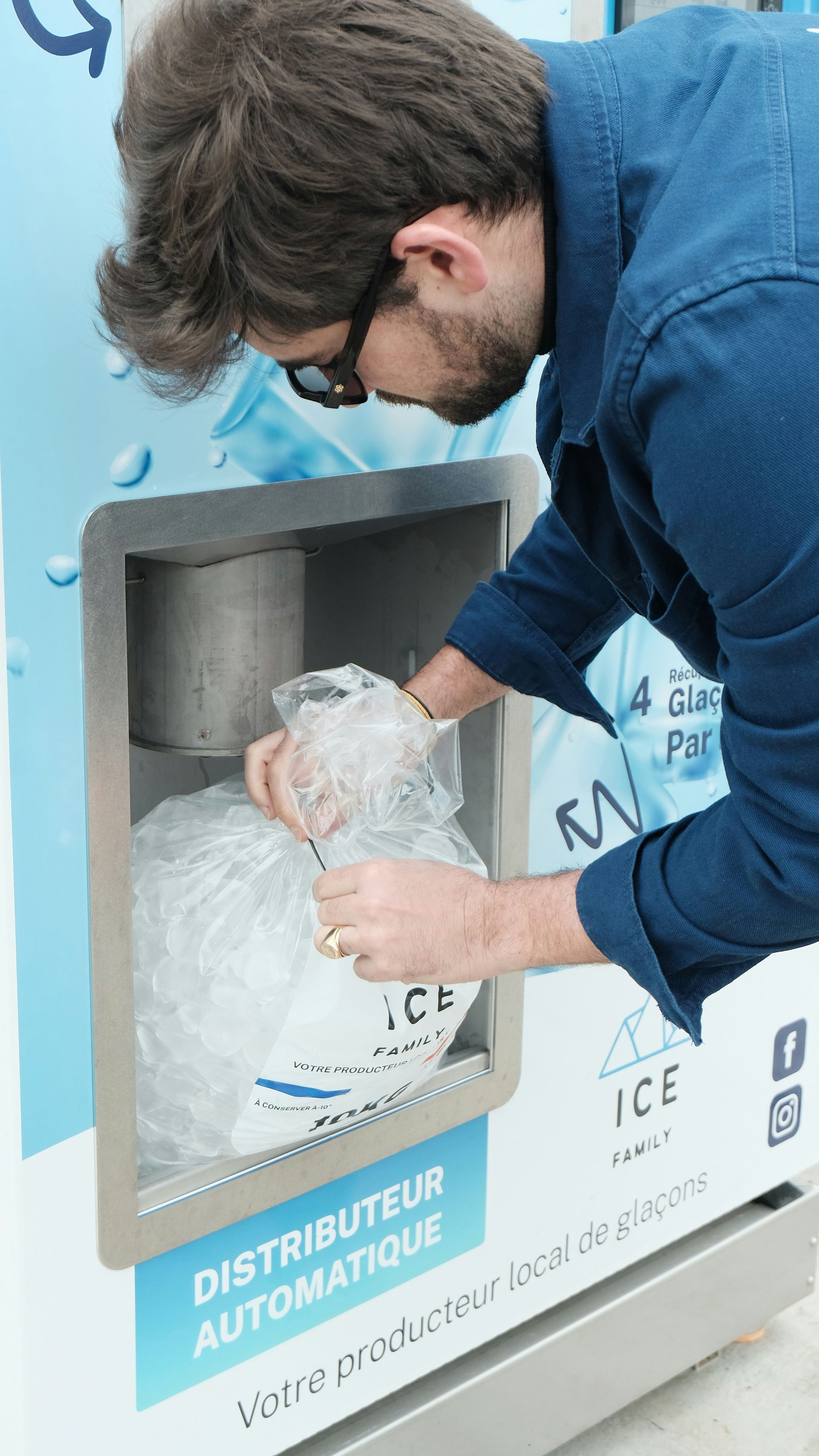 Man filling a large water bottle at a blue self-service water dispenser