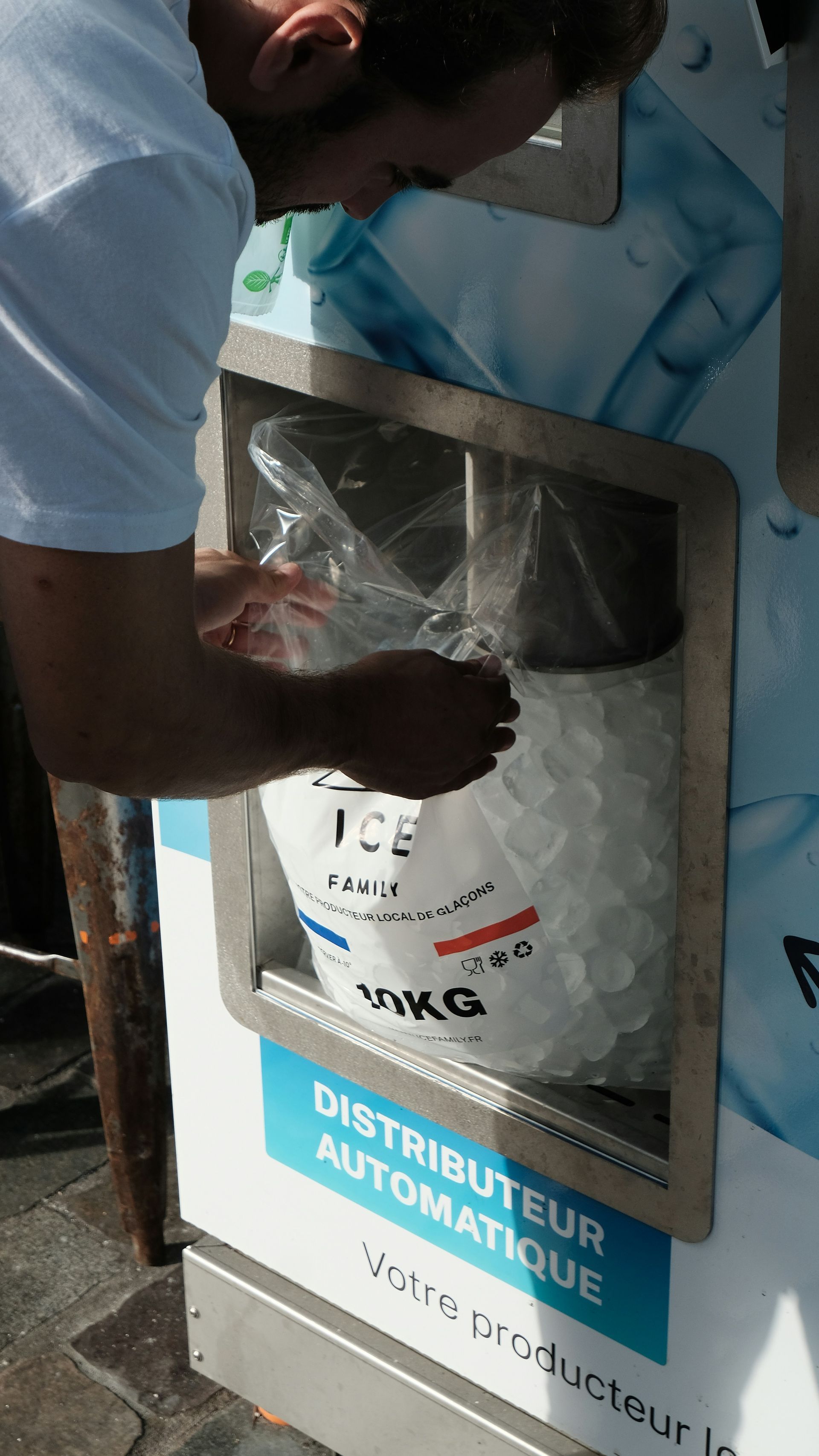 Person opening a plastic water refill bag at an automatic distributor machine