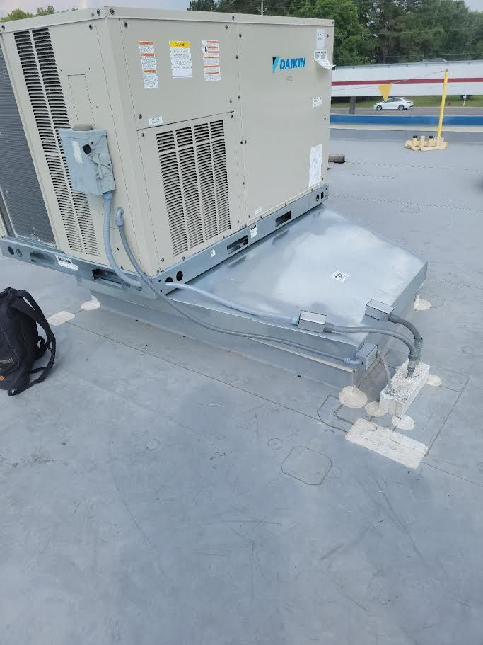Large HVAC unit on a rooftop with a metal support frame and power cables nearby
