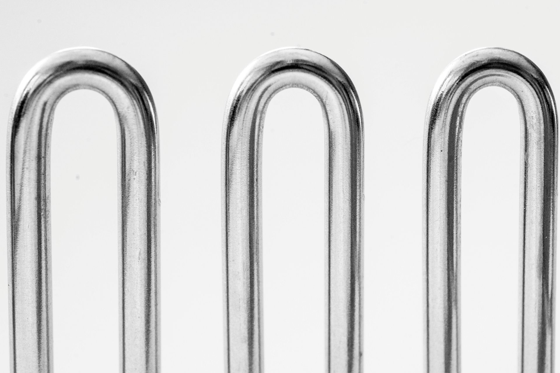 Three chrome paper clips standing upright on a white background