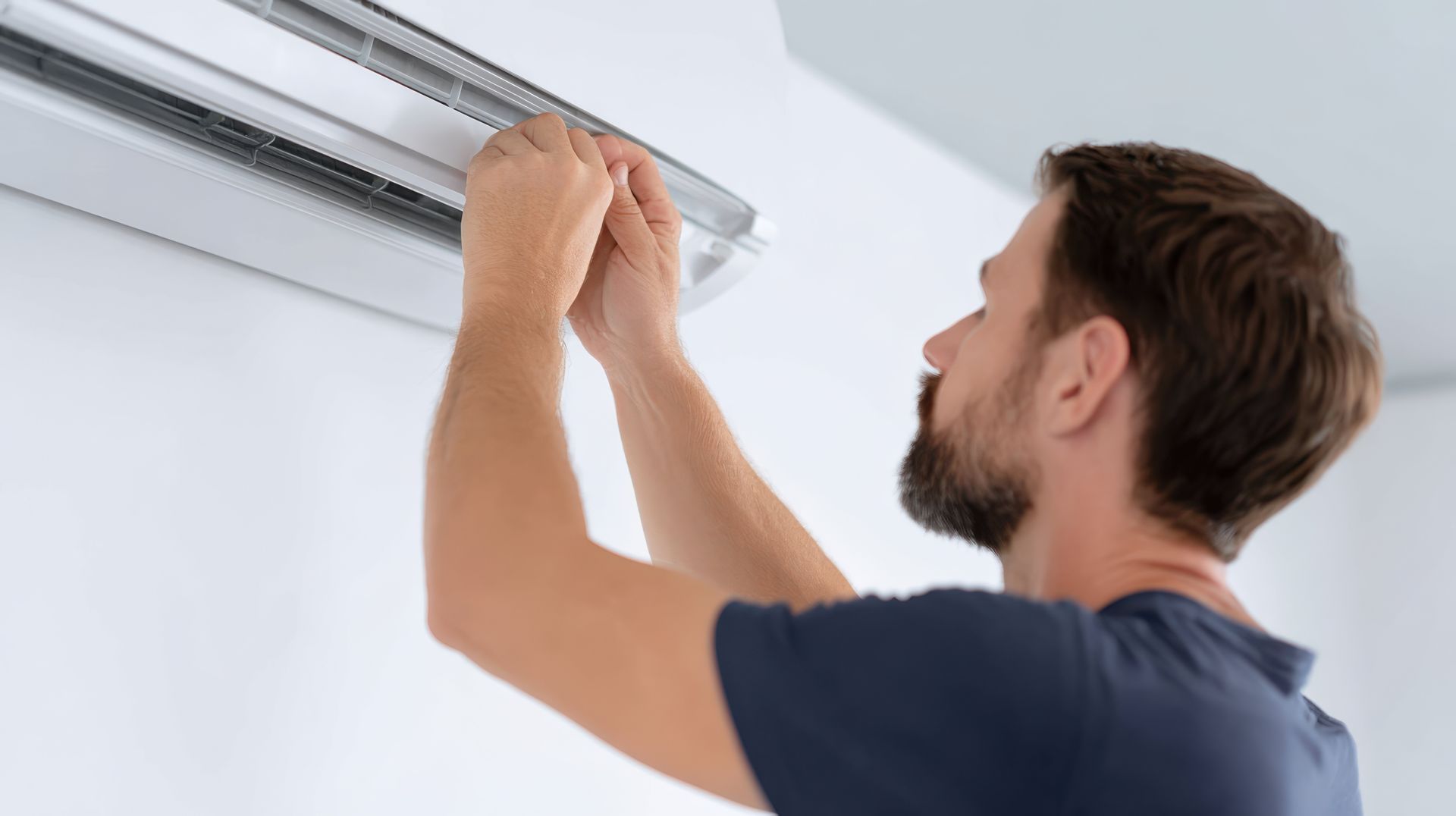Man adjusting a window blind on a white wall using both hands