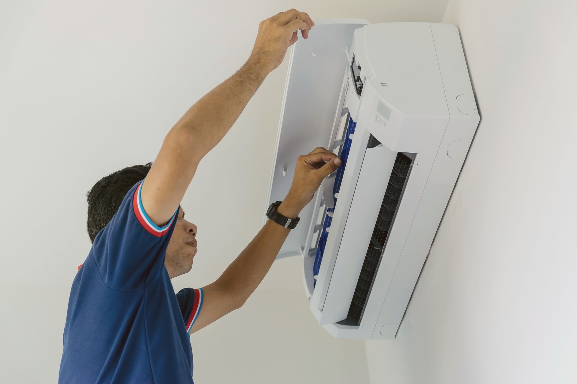 Technician adjusting a wall-mounted air conditioner with tools