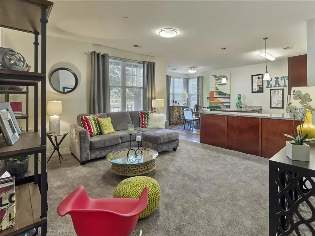 Living room with plenty of natural light, and kitchen in background