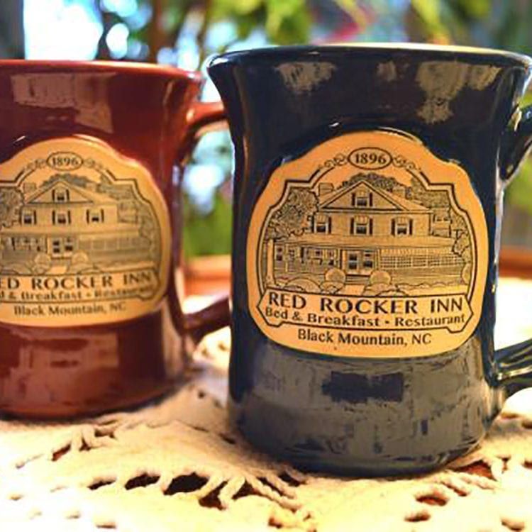 Two mugs, one burgundy, one navy, feature the Red Rocker Inn logo.