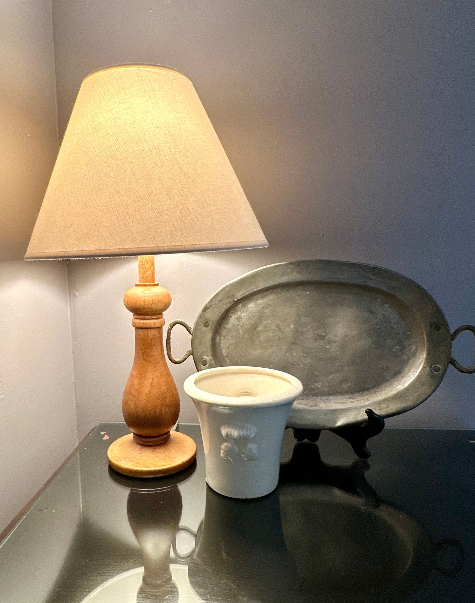 Bedroom with a white bed, wooden table, patterned rug, and grey walls. Sunlight streams through the window.