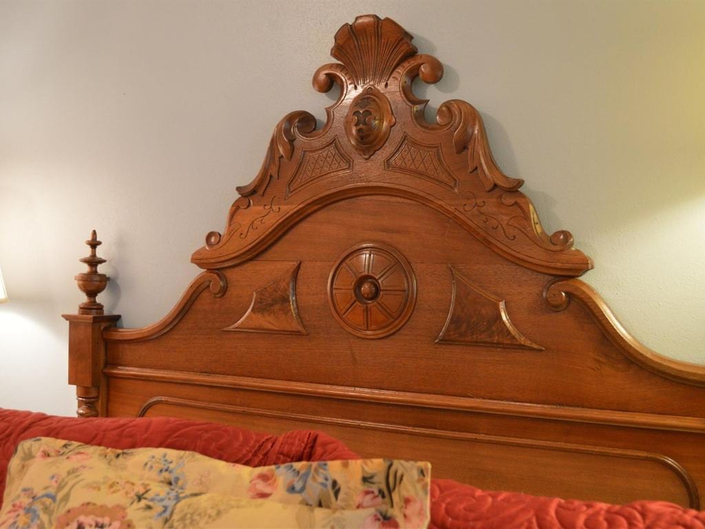 Wooden headboard with ornate carved details, including a central medallion and decorative crest.
