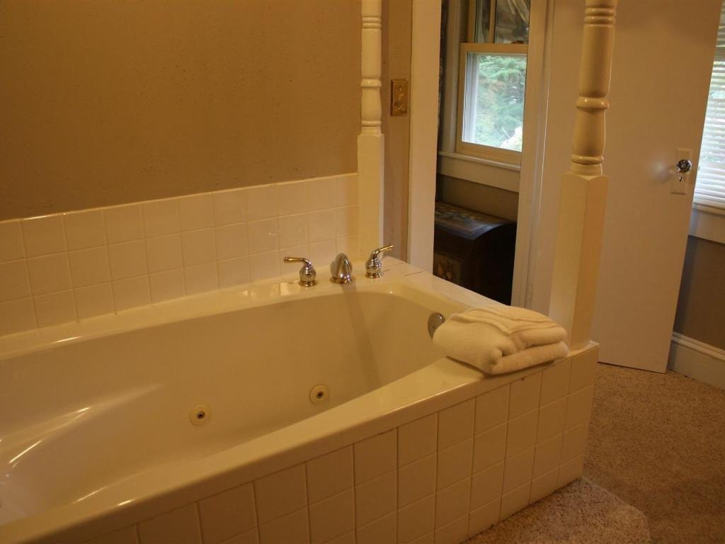 A white jacuzzi tub with a towel sits in a bathroom. A doorway to another room is visible.