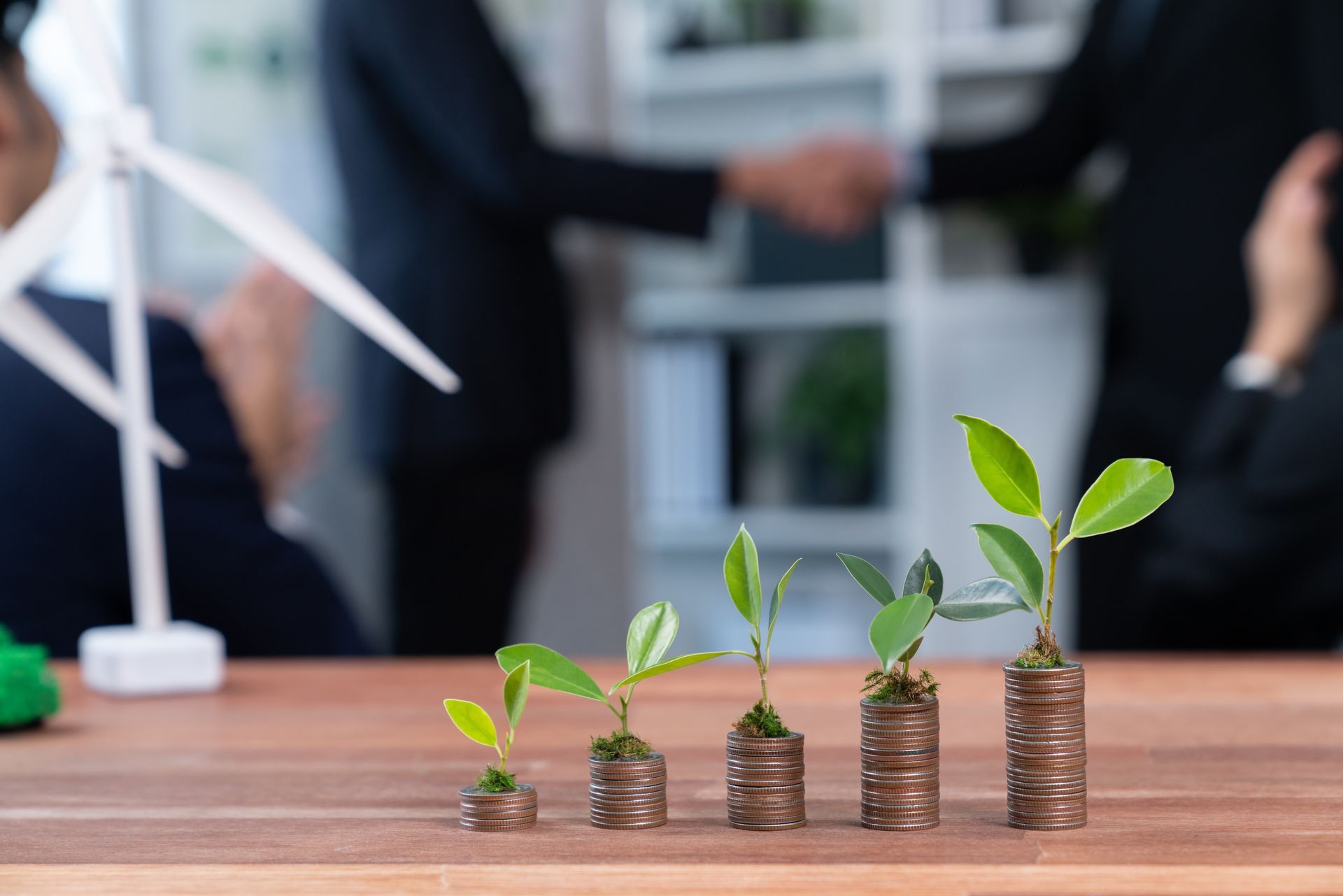 A group of plants growing out of stacks of coins on a table.