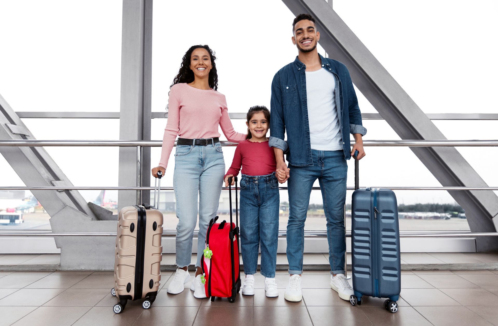 Family of three with luggage smiling in an airport.