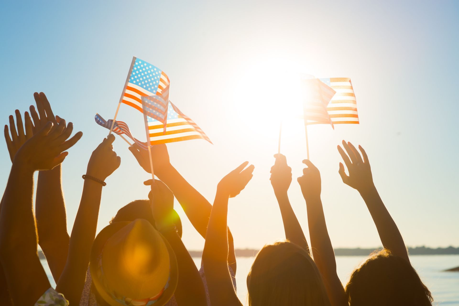 A group of people are holding American flags in the air.