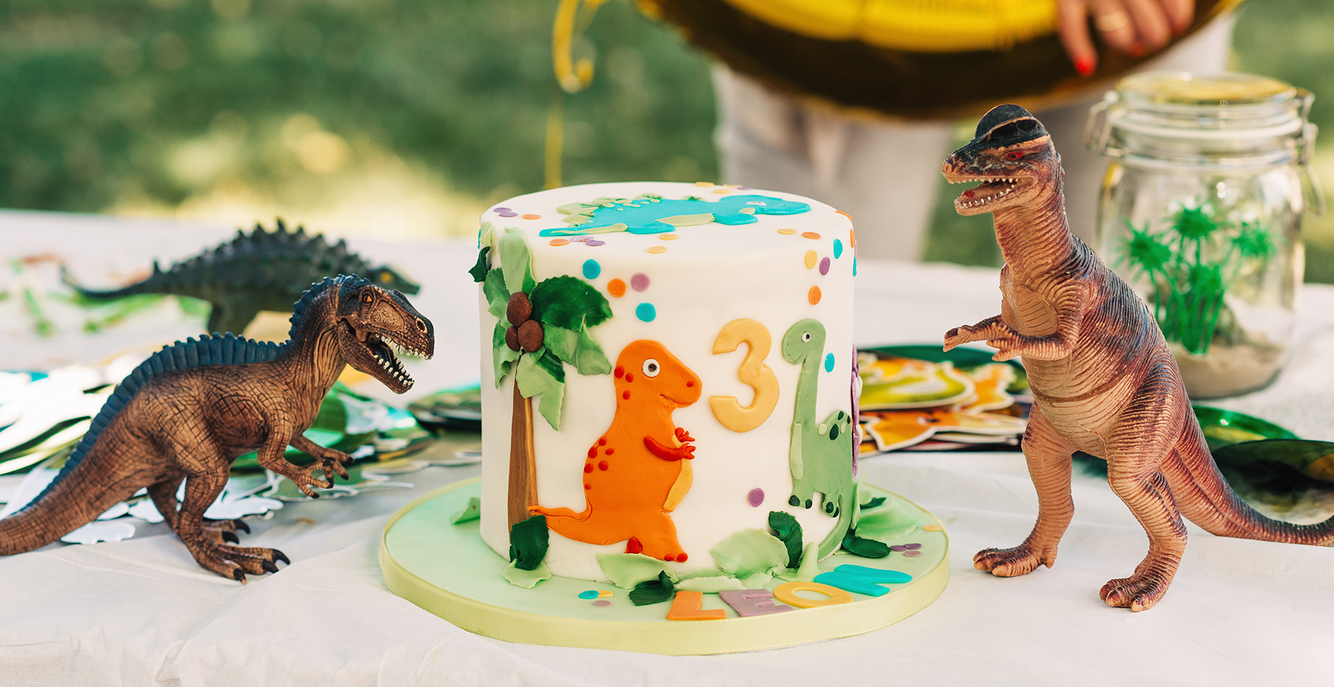 a dinosaur themed cake and plastic dinosaurs on a party table