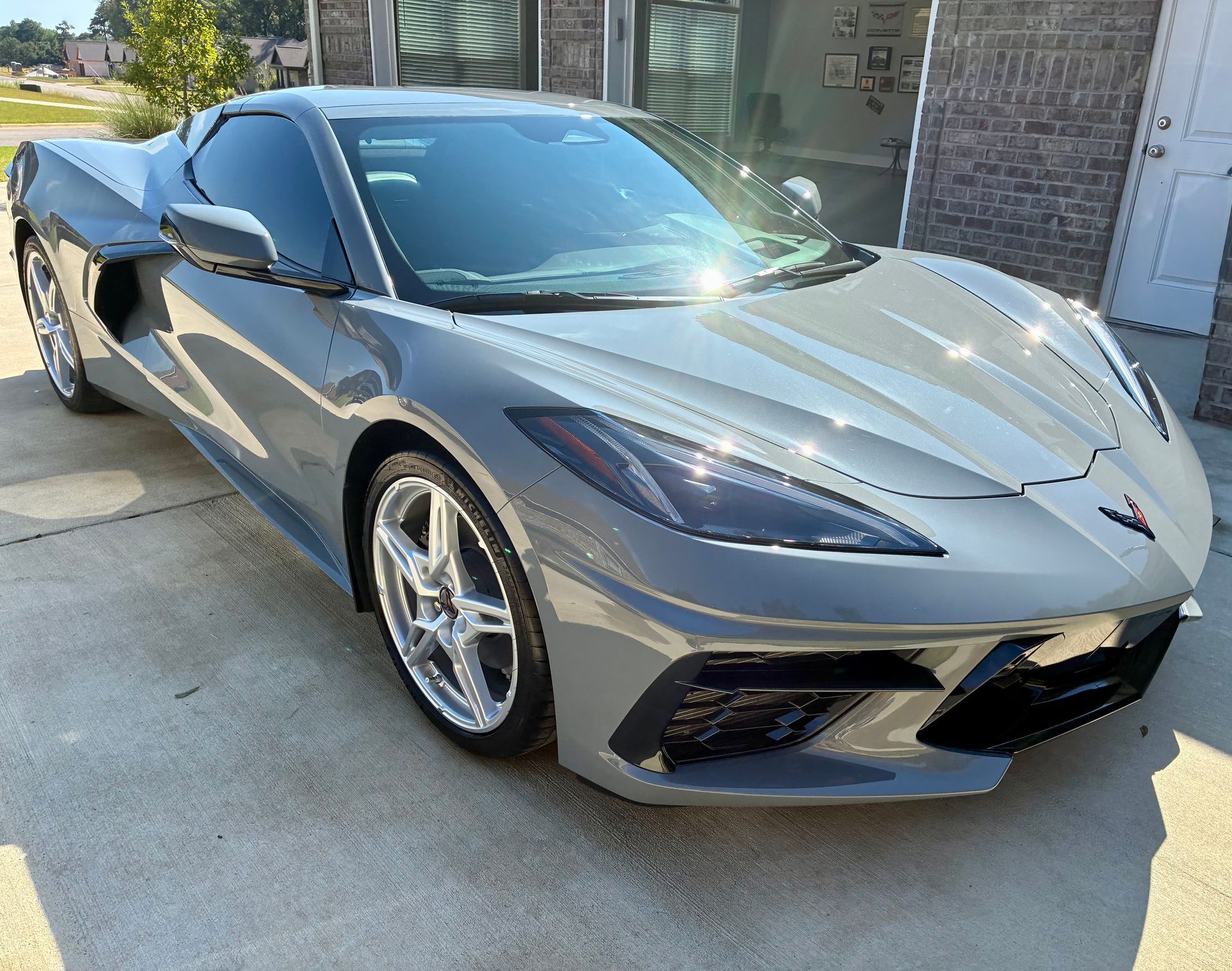 Gray Chevrolet Corvette sports car parked in front of a house.
