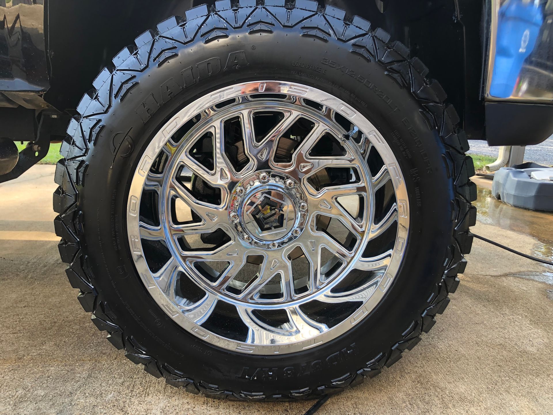 Shiny chrome wheel on a black truck, with black off-road tire.