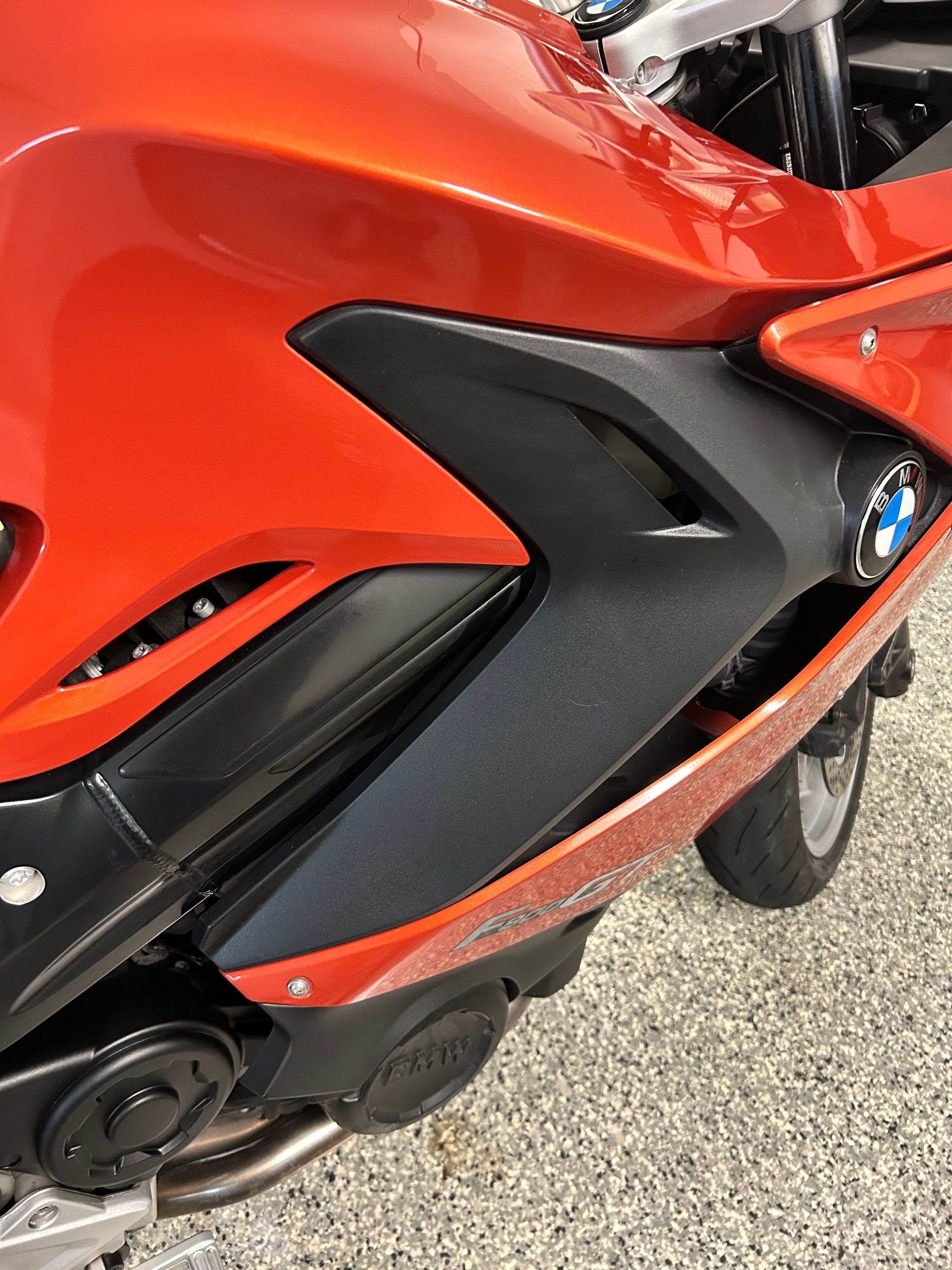 Orange and black BMW motorcycle side panel with logo.