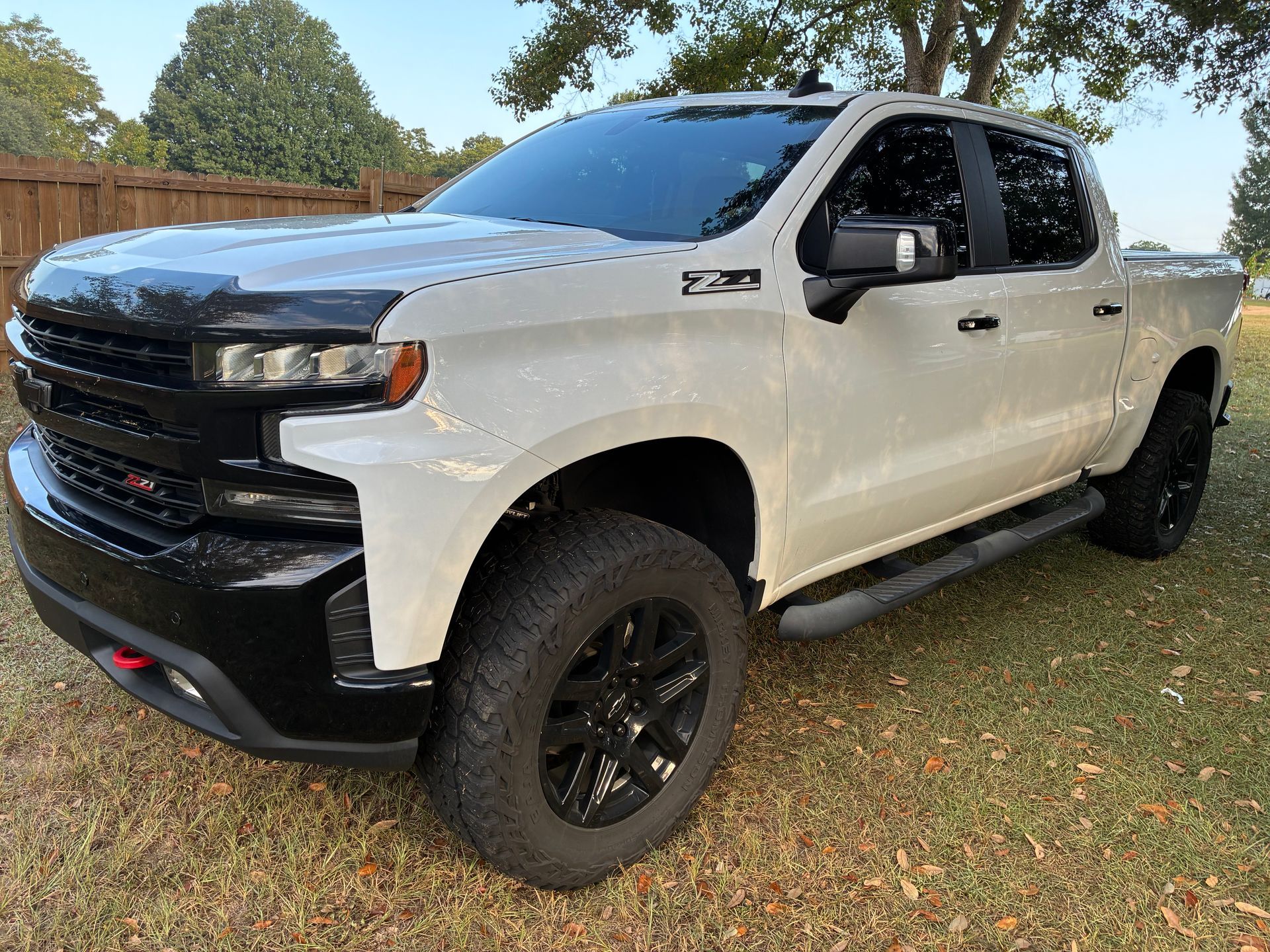 White Chevrolet Silverado pickup truck with black accents and wheels, parked on grass.