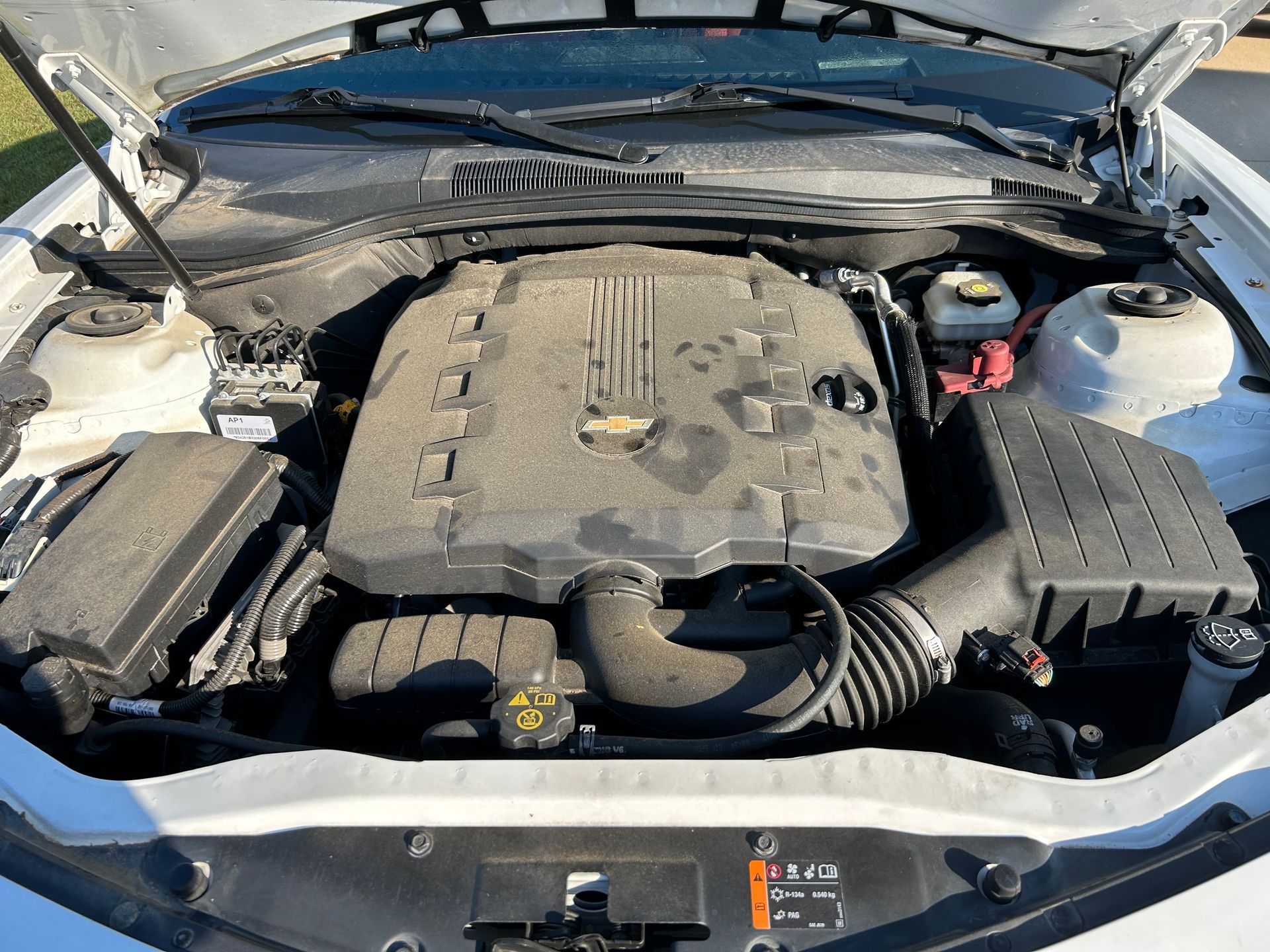 White car engine, dusty, with black engine cover.