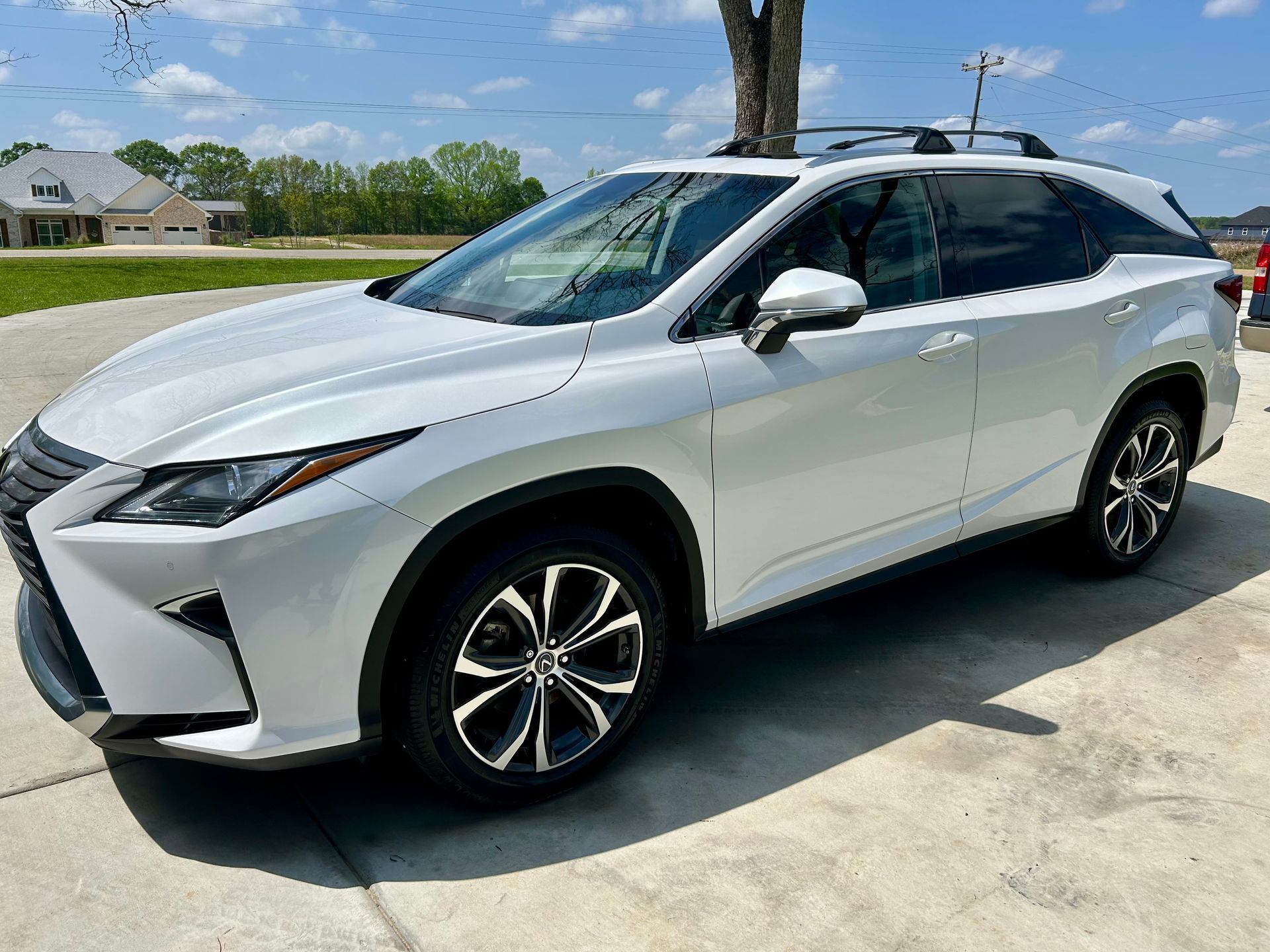 White Lexus SUV parked on a concrete driveway on a sunny day.